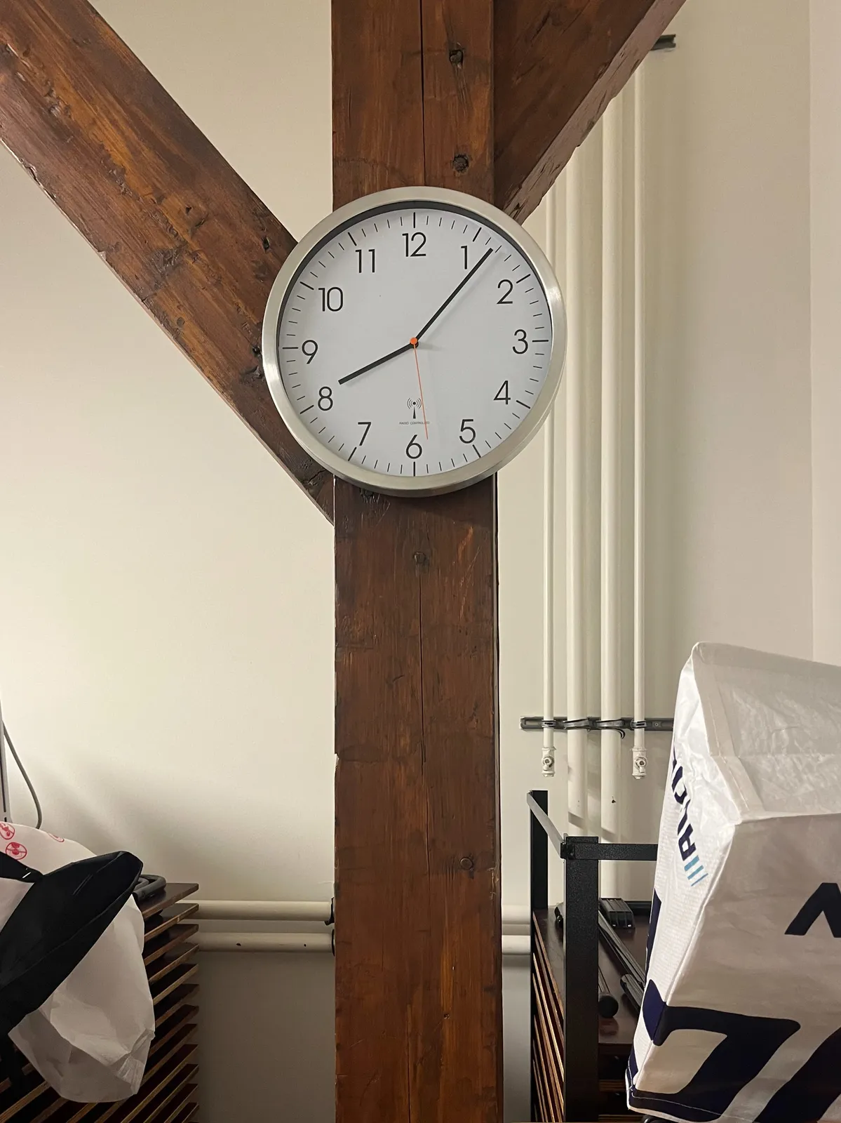 A clock attached to old wooden roof beams. It points at 11 minutes past 8.