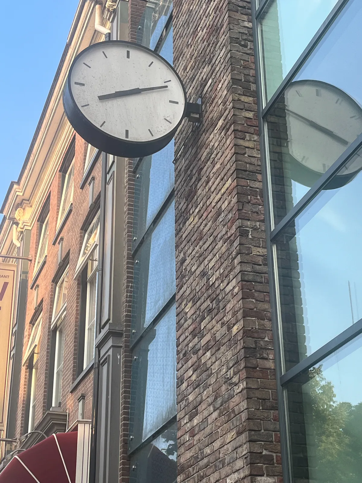 A modernist clock attached to the facade of a building. it points at 11 minutes past 8.