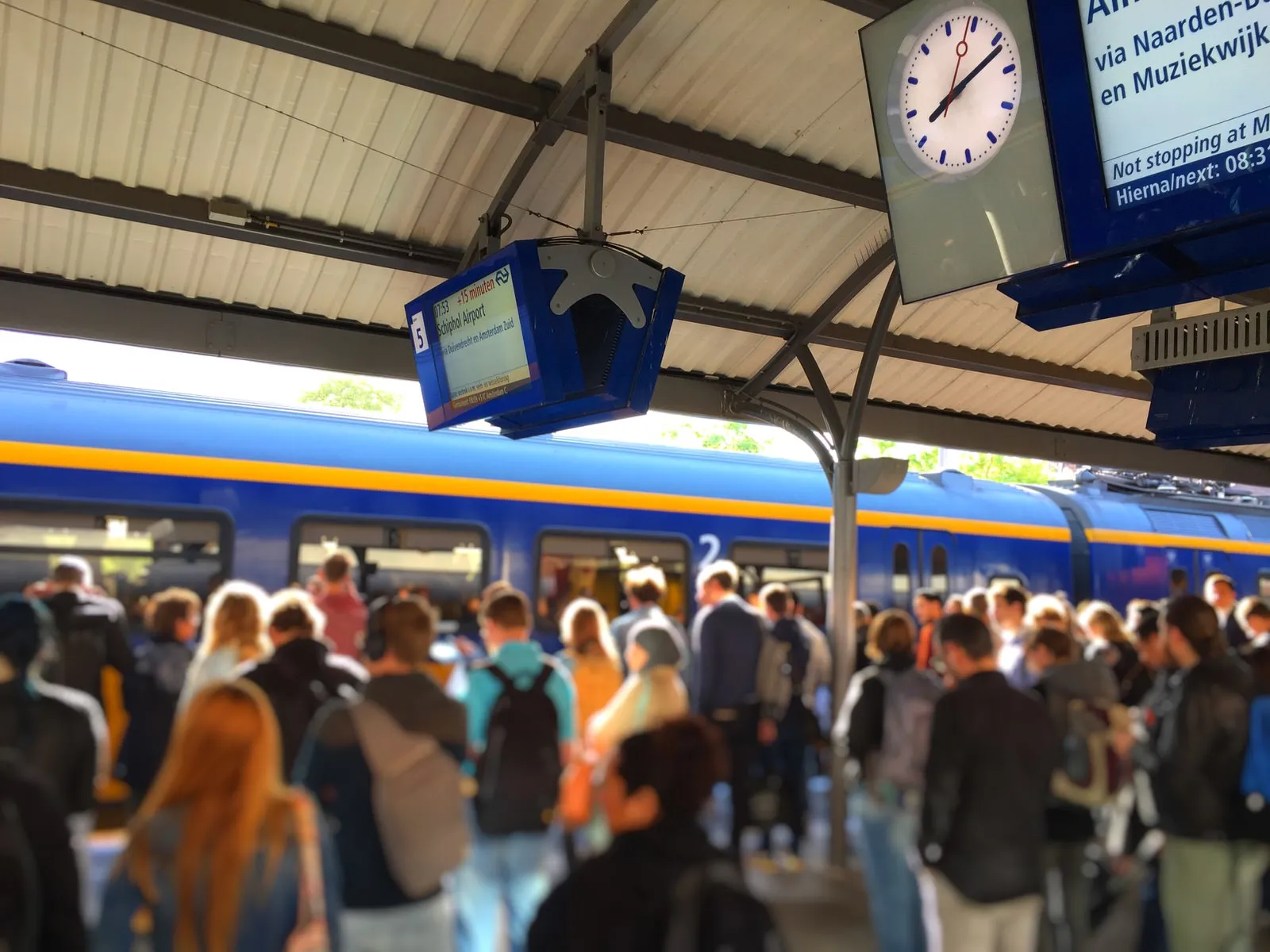 Many many people on this picture, all blurry. The clock is sharp and it points at 12 past 8.