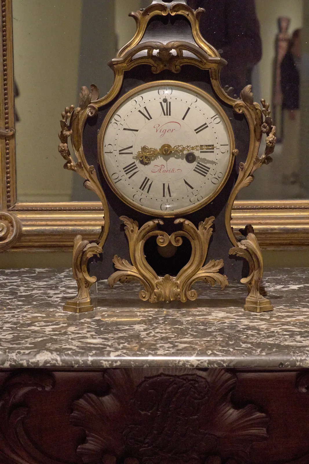 A golden, ornamented mantel clock, made by Viger in Paris. It points at 14 minutes past eight.