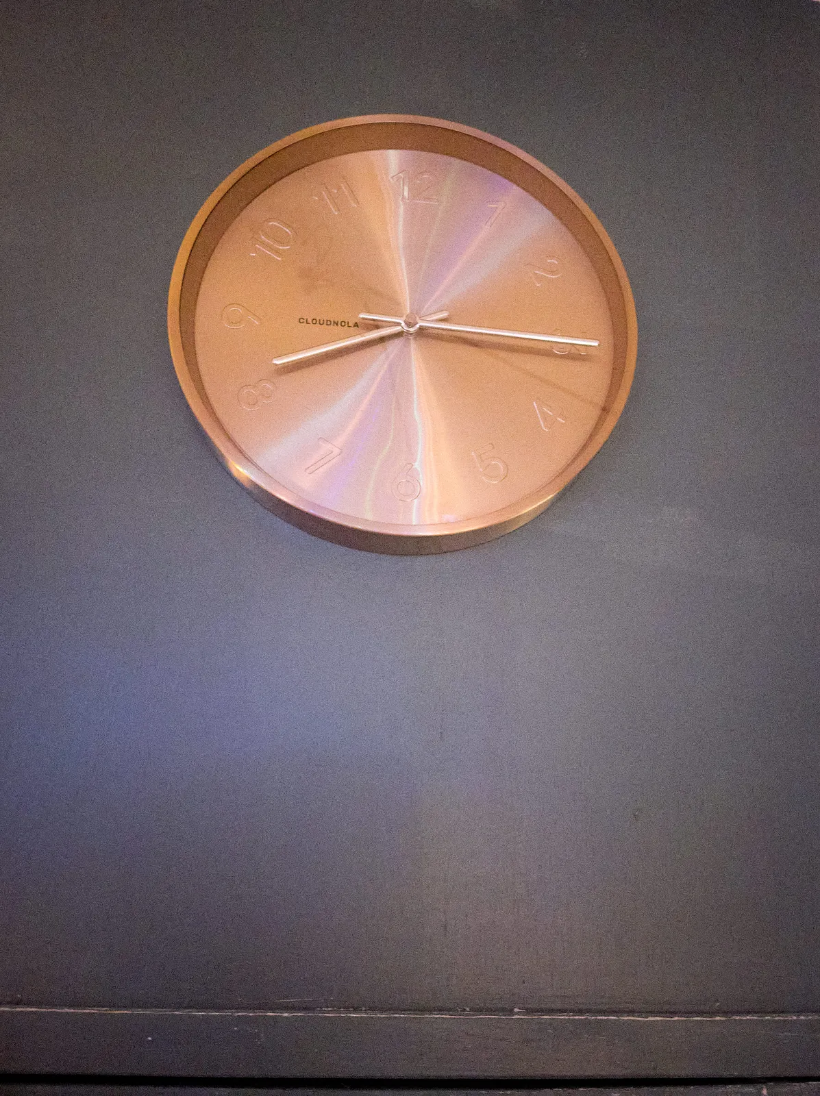 A pink golden clock on a wall. It points at a quarter past 8.