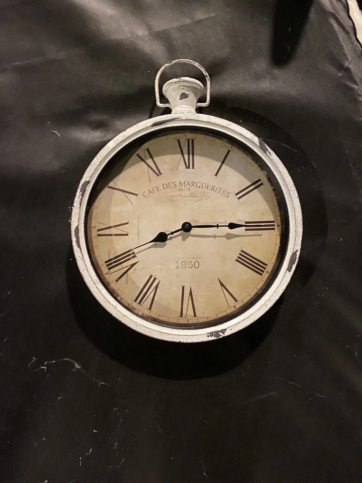 This clock seems to be from 1950. The words CAFE DES MARGUERITES is printed on its face. On it the time is a quarter past 8.
