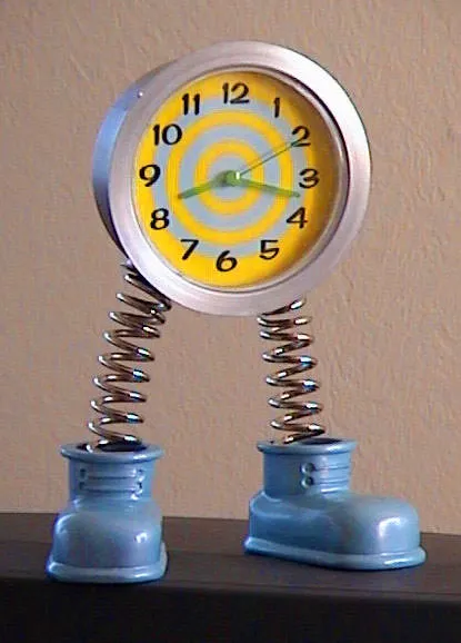A clock with two bouncy feet points at 17 past eight.