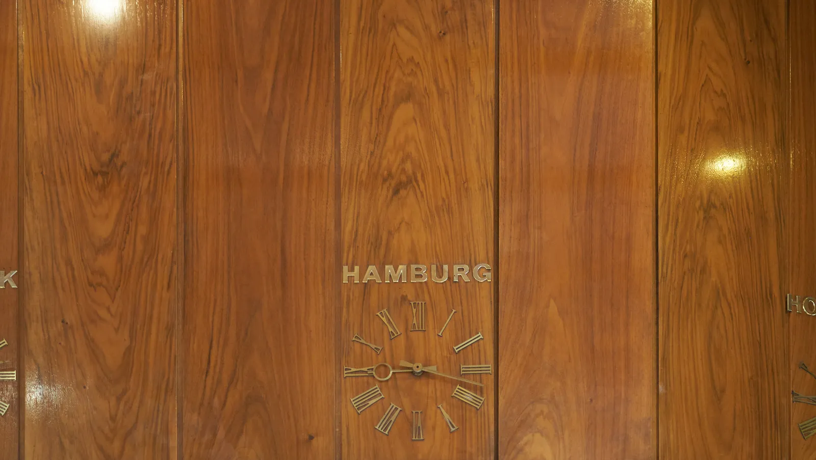 A lathed wall with a built in clock. Above the clock it says Hamburg. The clock points at 17 minutes past 8.