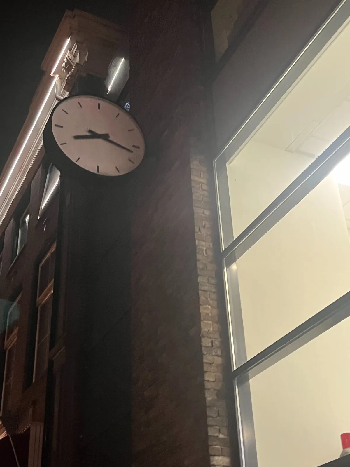 A clock attached to the facade of a brick building. It points at 17 minutes past 8.