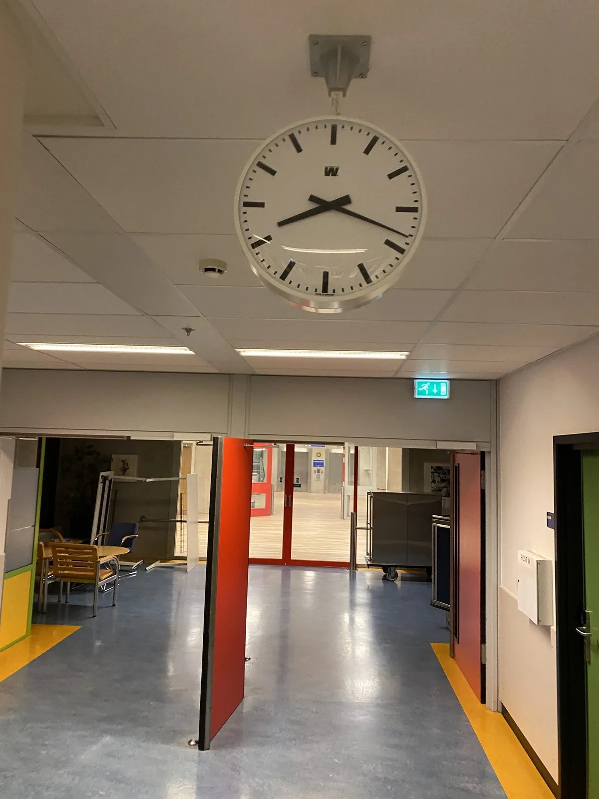 A clock attached to a ceiling. It points at 18 past 8.