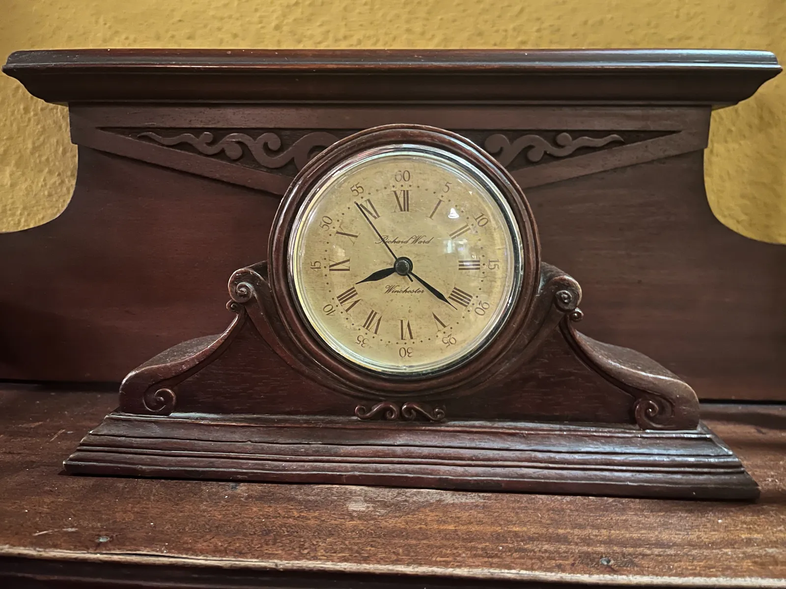 A wooden clock that seems to be built into a wooden cabinet. It points at 22 past 8.