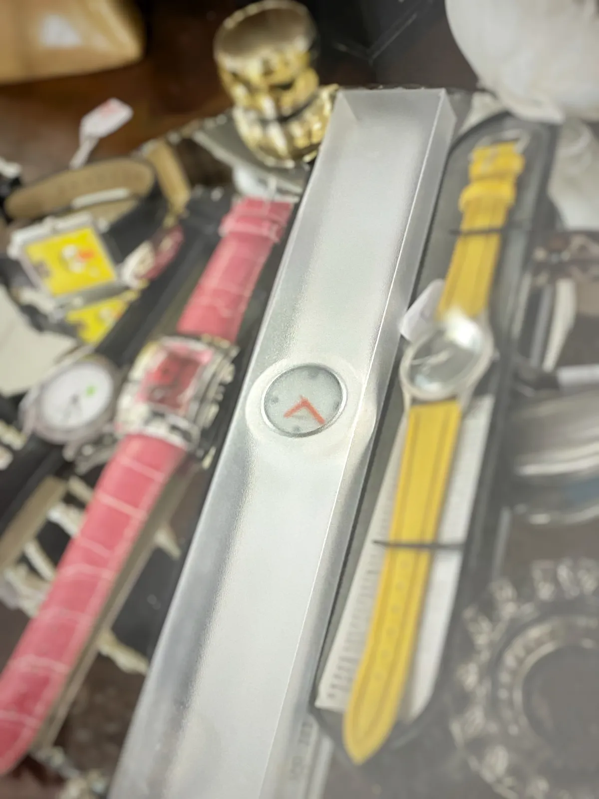 A white wirst watch in a semi transparent plastic box. Only the part that covers the face of the watch is fully transparent. It points at 22 past 8.