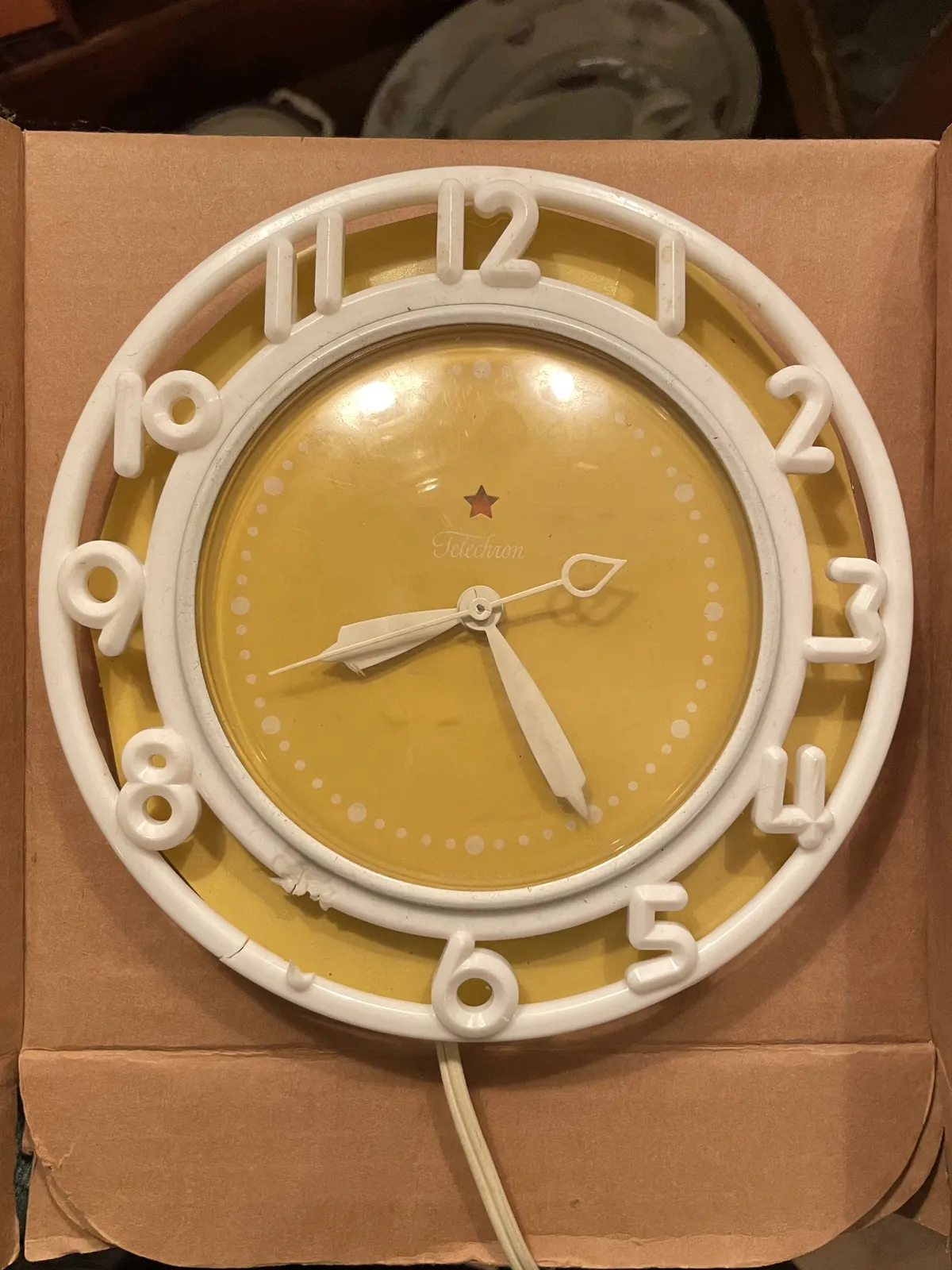 A yellow clock with white numbers, and white circles. The number 7 is broken off. The clock points at 25 past 8.