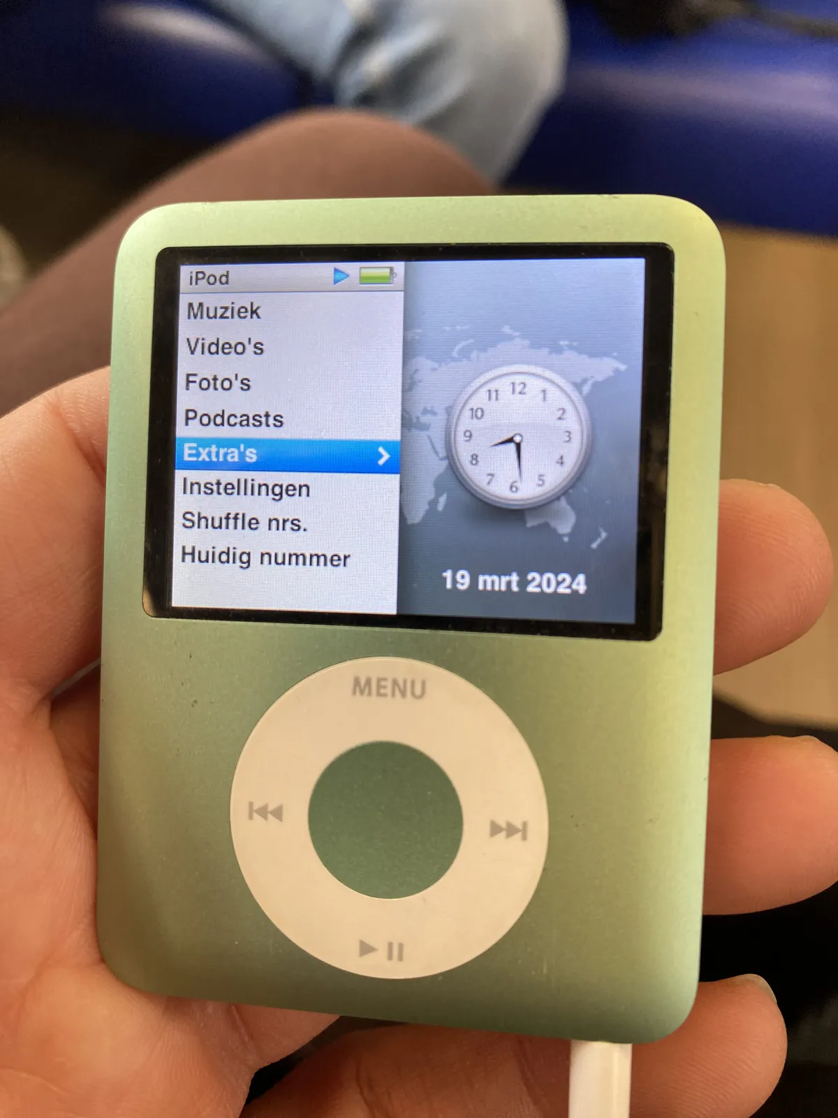 An iPod with a colourful screen. On it there’s an analogue clock that points at 29 minutes past 8.
