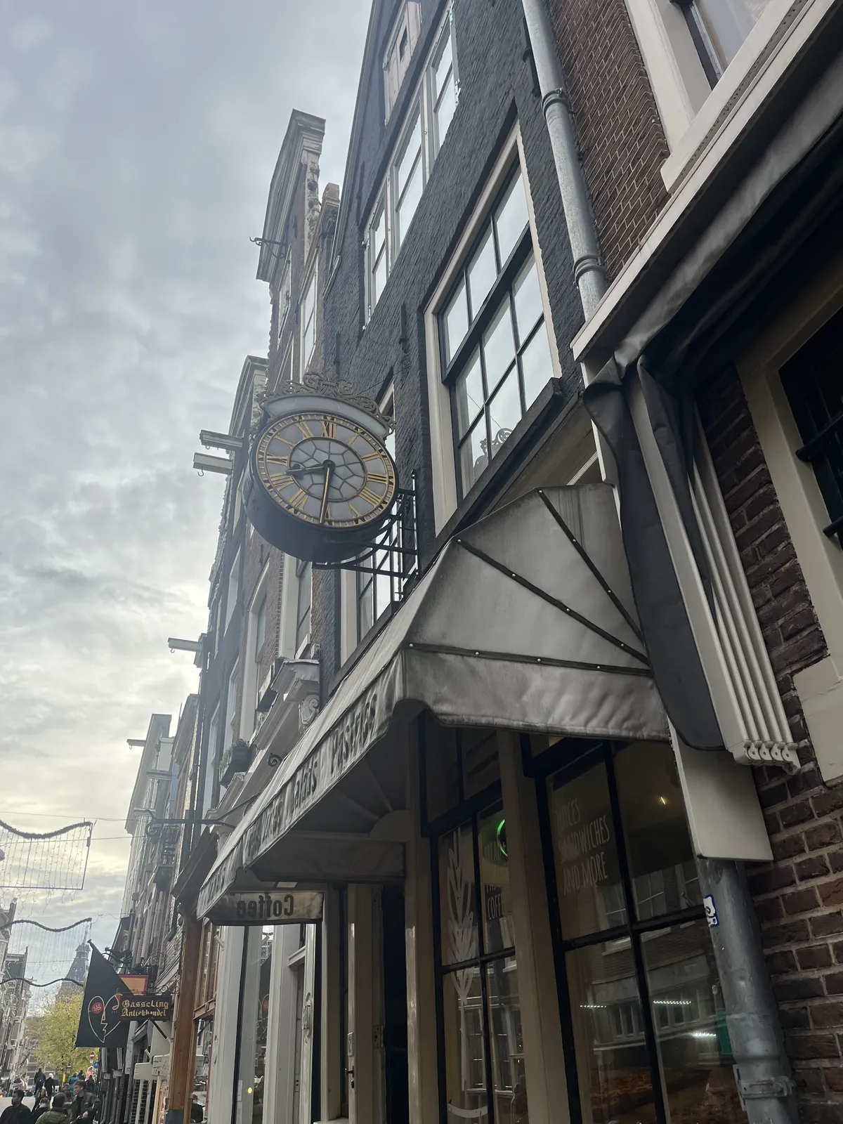 An old clock attached to the facade of an old building in an old Amsterdam shopping street. The clock points at 31 minutes past eight.