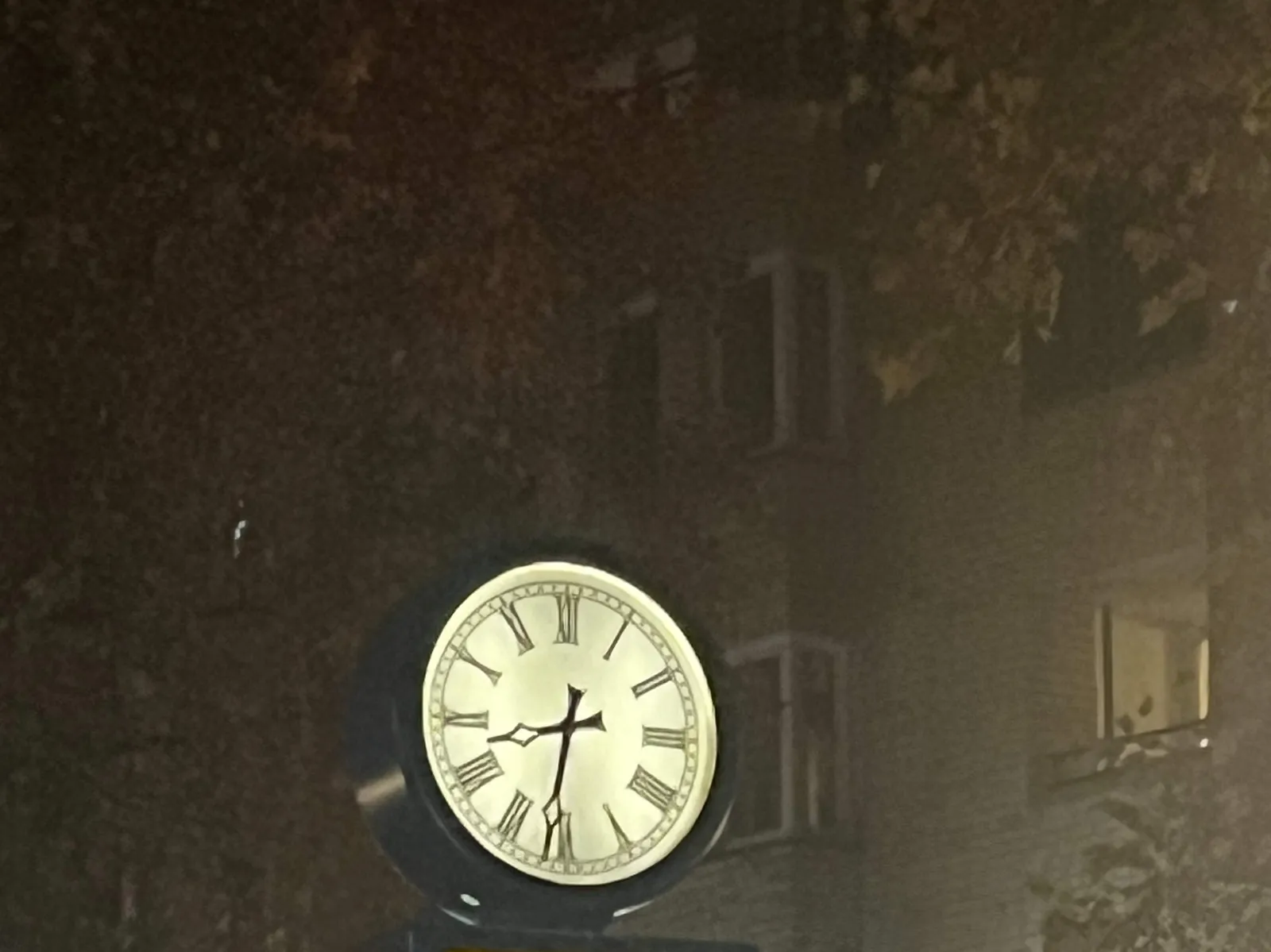 A classic, lit clock against a dark background. It points at 29 minutes to 9.