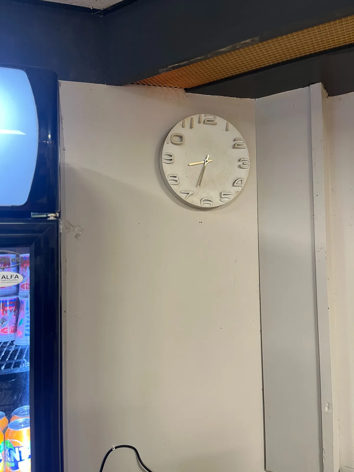 A white clock on a white wall. It points at 28 minutes to 9.
