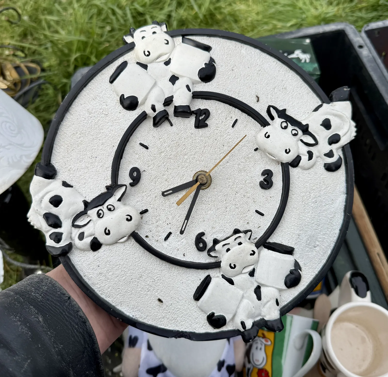 A novelty clock with four happy, cartoon cows on the three, the six, the nine and the twelve. The clock points at 33 minutes past eight.