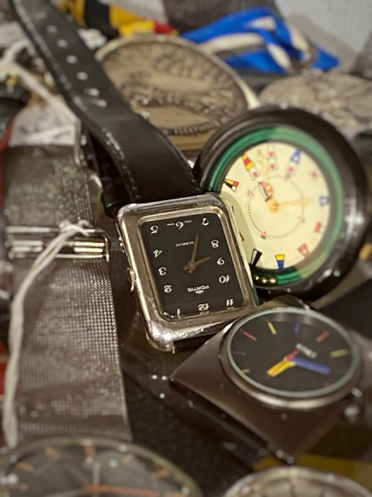 A collection of quite a few watches. Most of them are too blurry to see the time, only one of them is in focus. It’s upside down, so it’s a bit harder to see that it points at 26 minutes to 9.