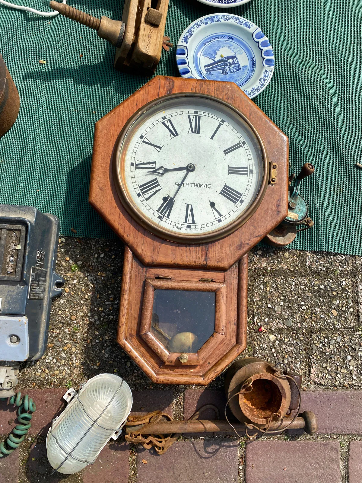 Old stuff for sale. Among the stuff is an old wooden clock. It points at 34 past 8.