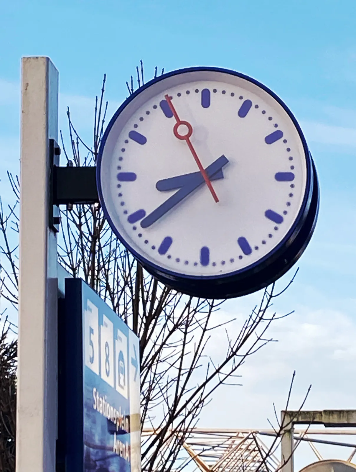 A clock in the open air, at a station in The Netherlands. It points at 22 minutes to 9.