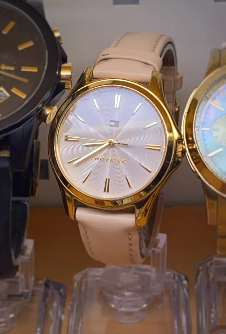 A golden Hilfiger watch. It points at 21 minutes to 9.