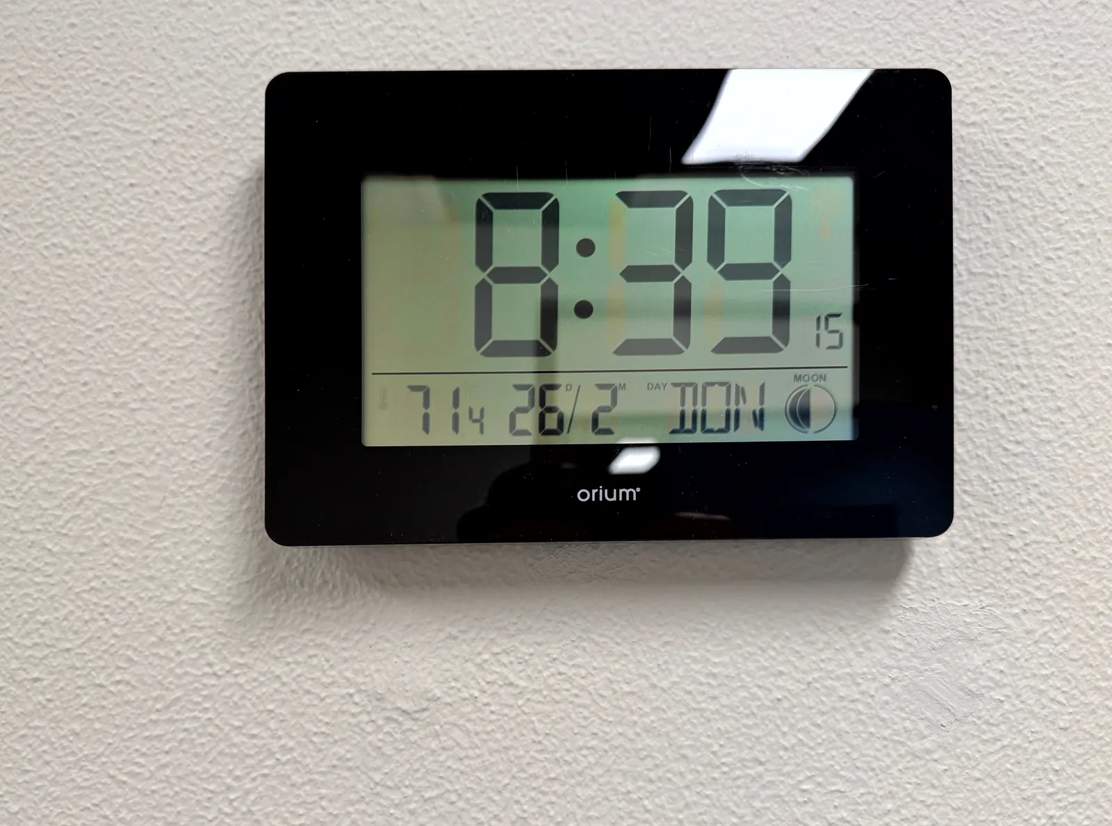 A digital device on a white wall shows all kinds of information. It says it is Thursday, the 26th of February, which is almost certainly not true. It also says it is half moon, which is also probably not true. And then it says, in large segmented numbers, that it is 8:39, which is probably true right now. 