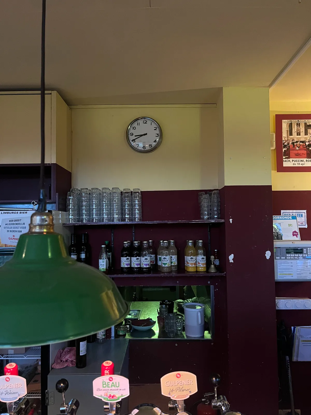 A clock on a wall in a bar. It points at 20 minutes to 9.