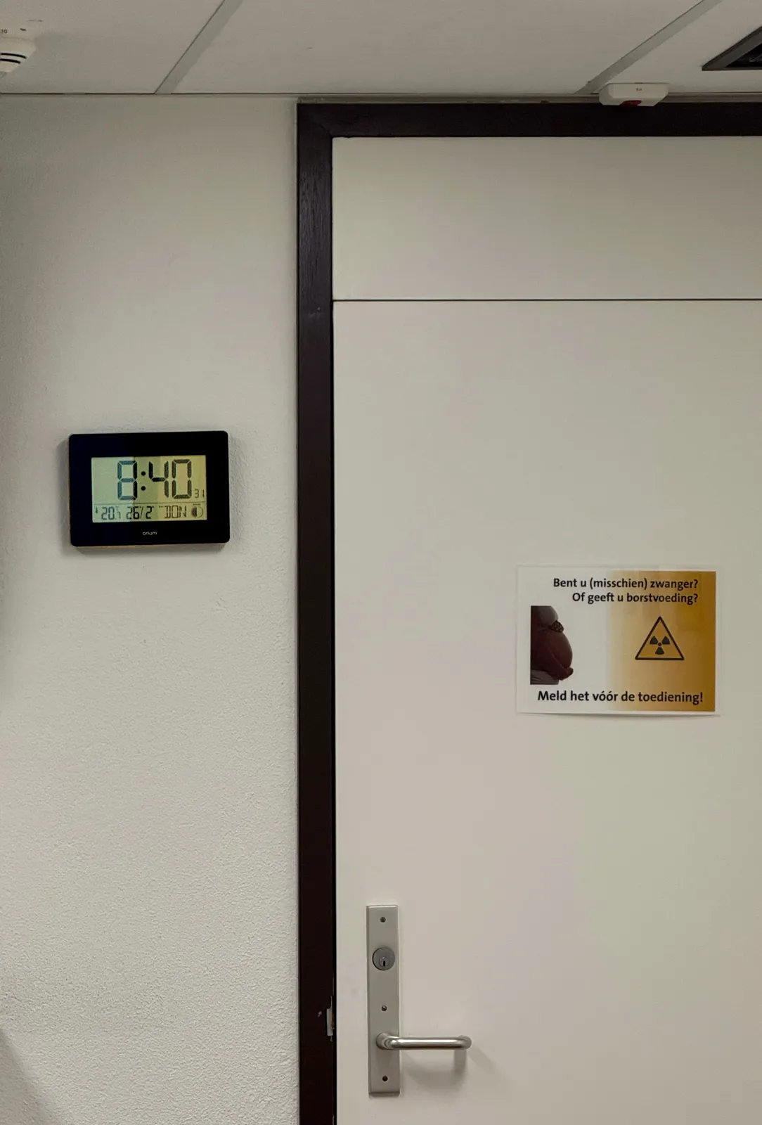 On a door there’s a sign with a radio-activity symbol on it, which says that you should mention it if you are (possibly) pregnant, or if you give breast feeding, Next to the door is a digital device. It shows all kinds of information. It says it is Thursday, the 26th of February, which is almost certainly not true. It also says it is half moon, which is also probably not true. And then it says, in large segmented numbers, that it is 8:40, which is probably true right now.
