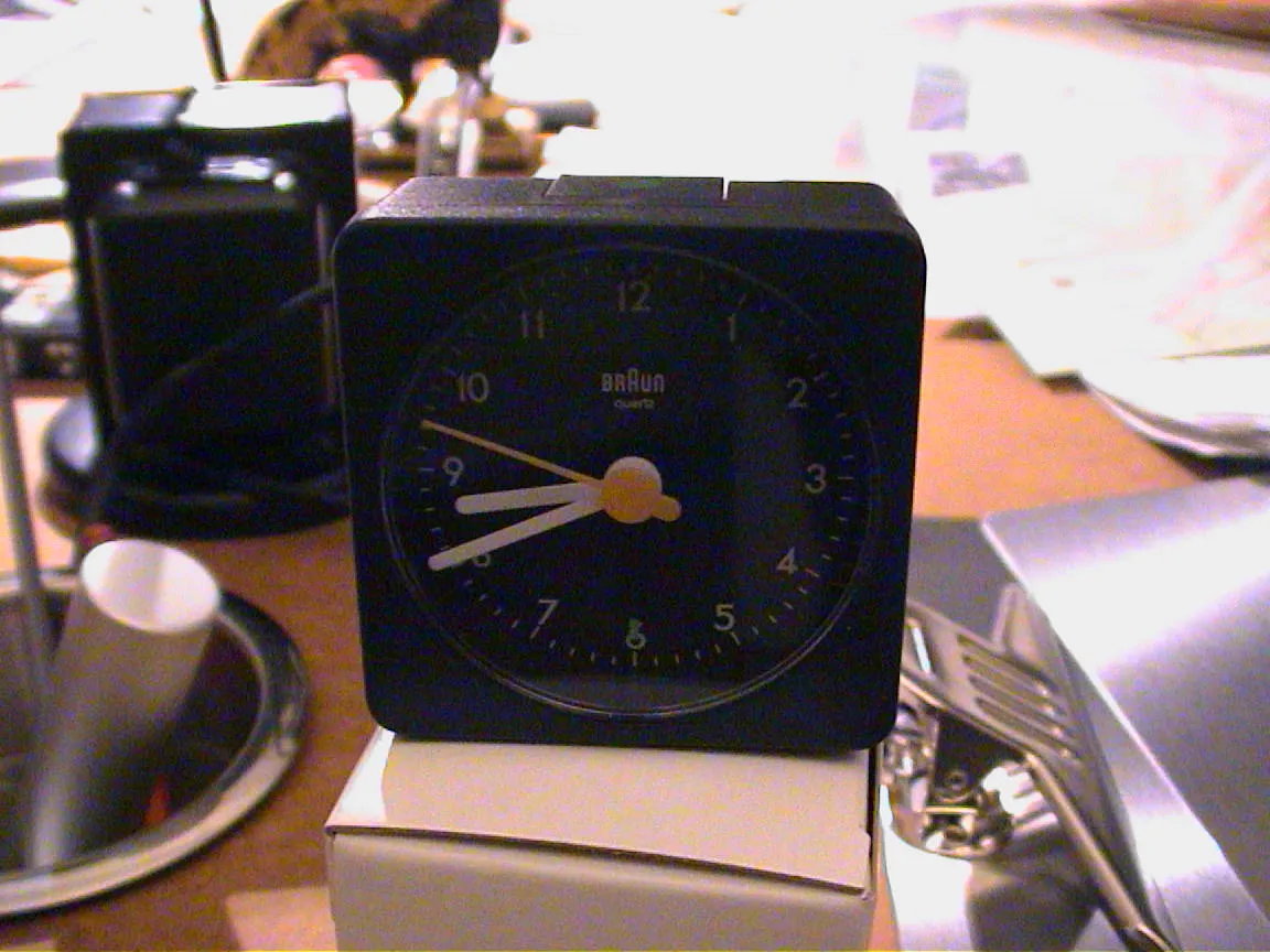 A small black travel clock tells the time. It is twenty to nine.
