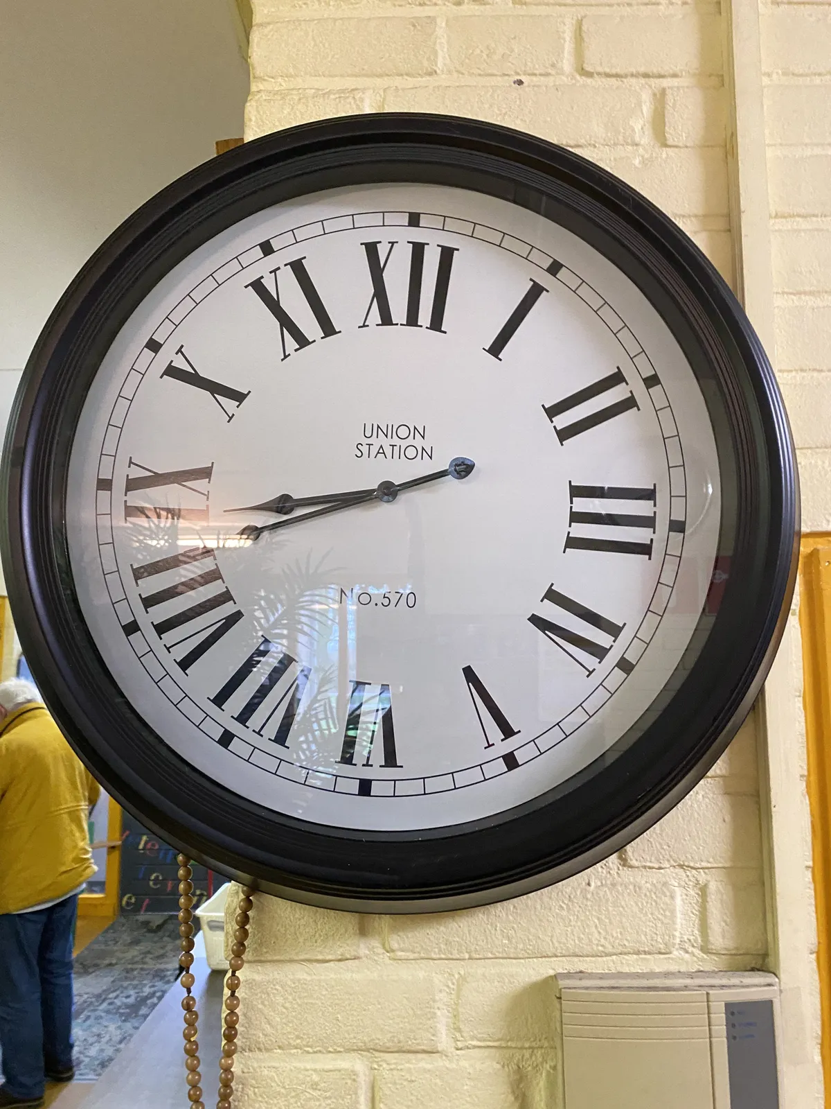 A large wall clock with large roman numerals. It says Union Station No 570 on its face and it points at 18 minutes to 9.