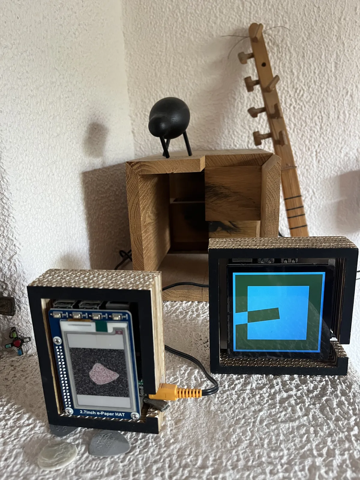 The top part of a saz, a Turkish musical instrument, and three art works. One of these works of art is a clock. It is not immediately clear what time it is, but once you get it you can see that it is approximately 16 minutes to nine.