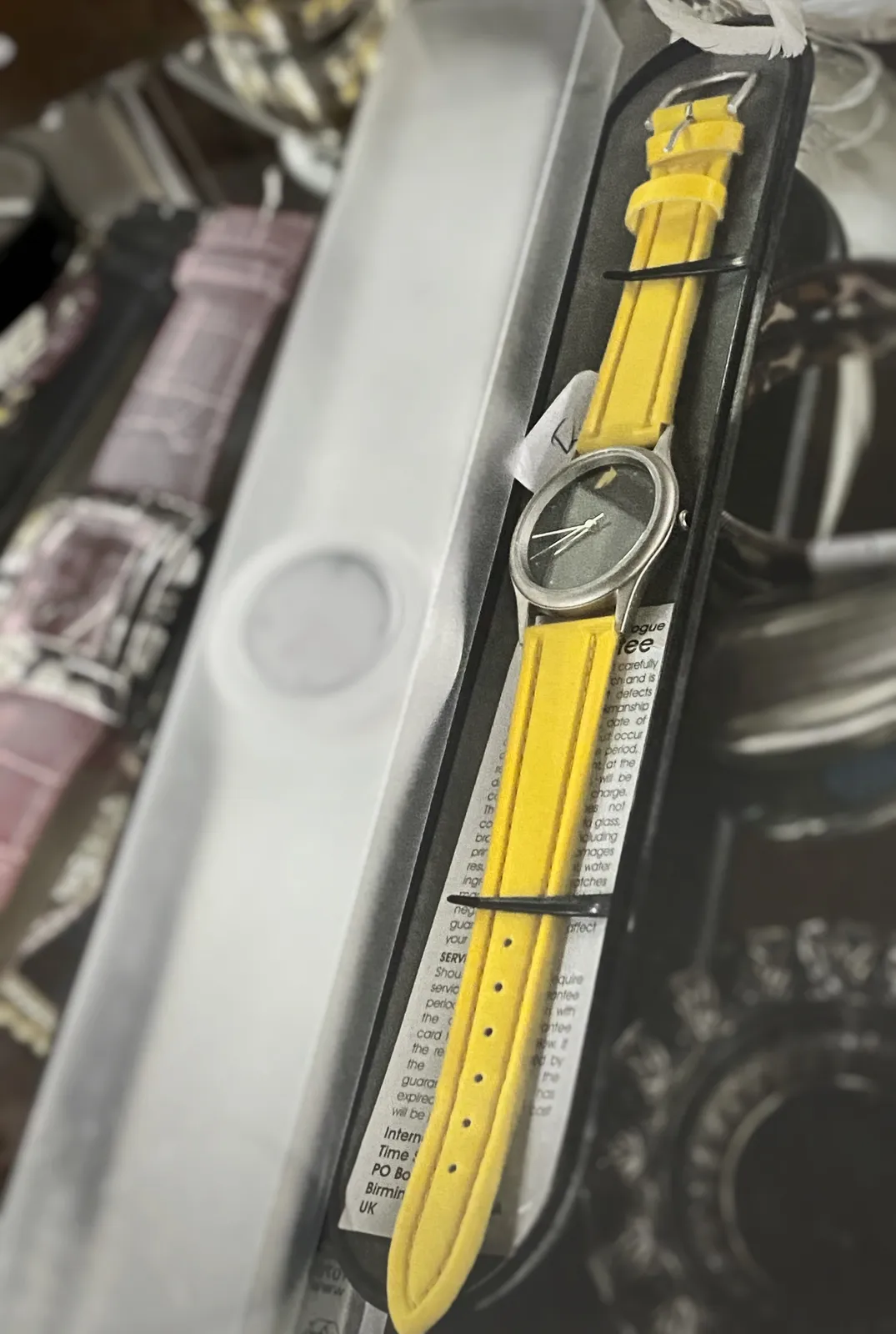 A watch with yellow bands. It points at a quarter to 9.