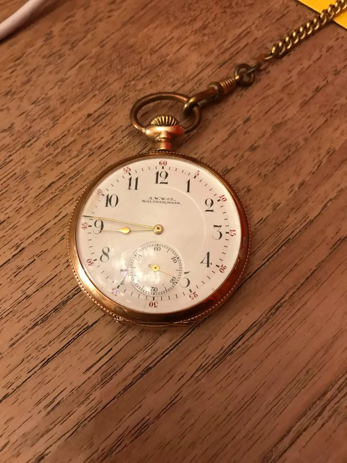 An old gold watch that points at a fourteen minutes to nine.