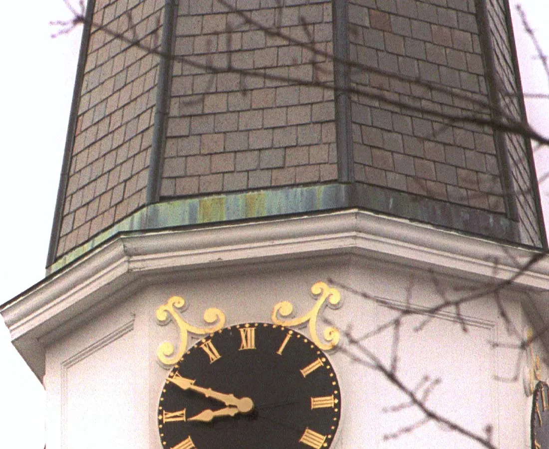 The clock on this church tower points at eleven to nine.