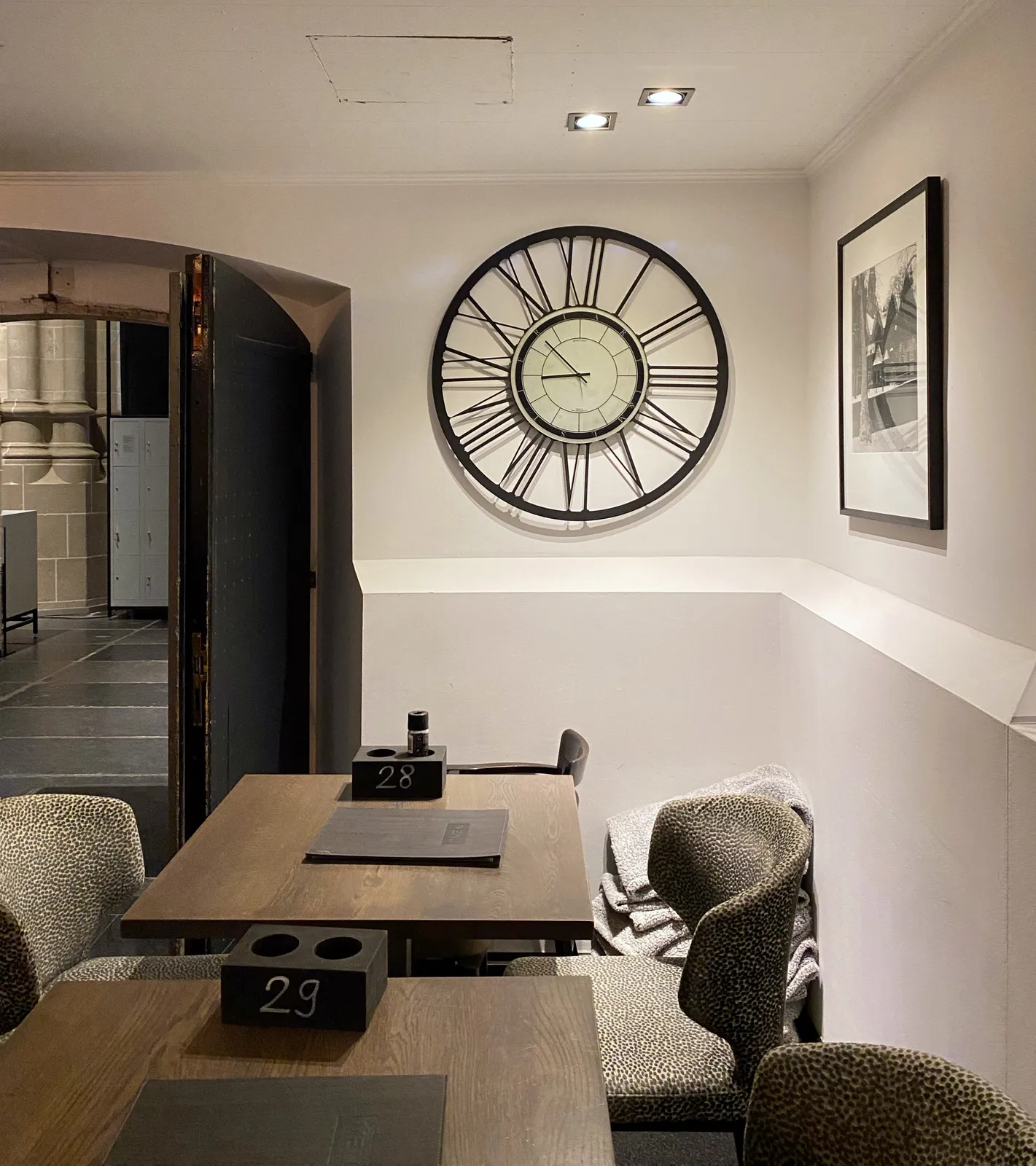 On the wall in a restaurant there’s a large clock. It points at 8 minutes to 9.