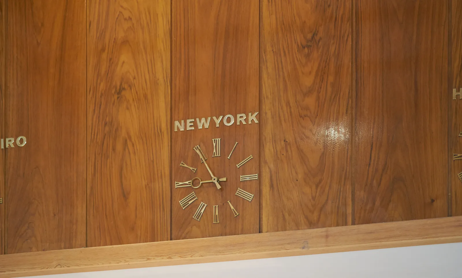 A lathed wall with a built in clock. Above the clock it says New York. The clock points at 5 minutes to 9.
