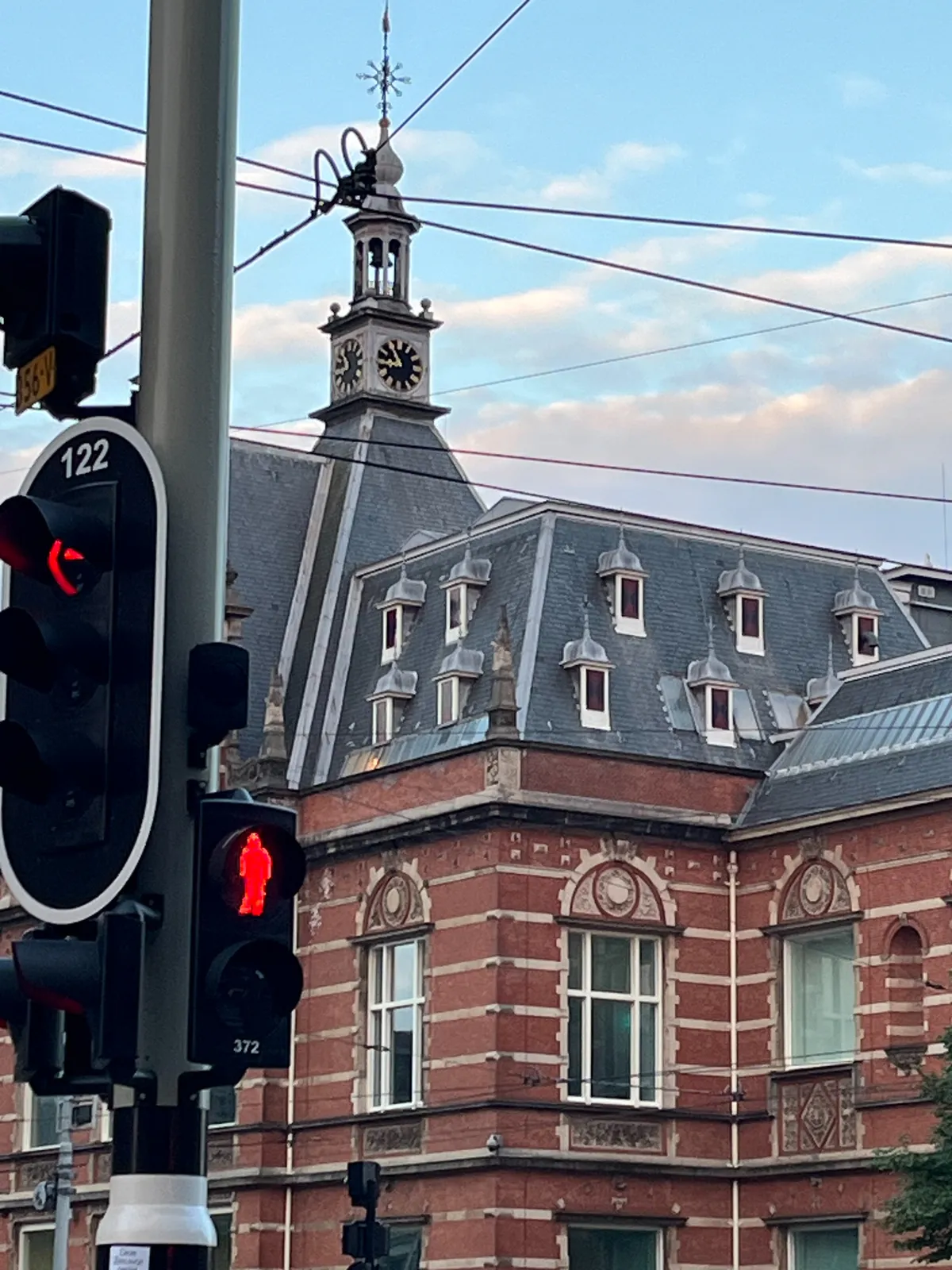 In the foreground the traffic light are all red. In the background there’s a building with a clock on its tip. It points at 5 minutes to 9.