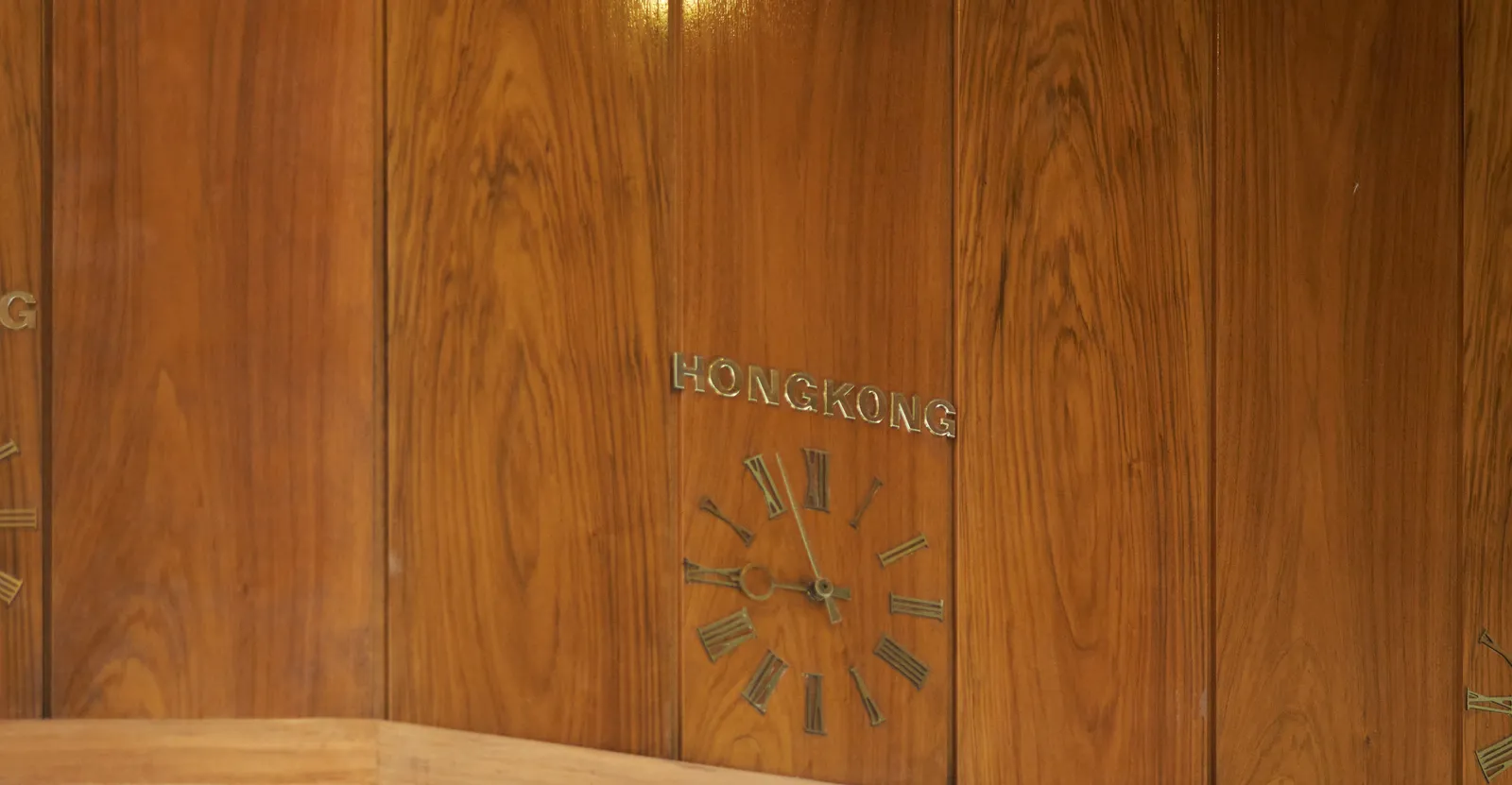A lathed wall with a built in clock. Above the clock it says Hongkong. The clock points at 3 minutes to 9.