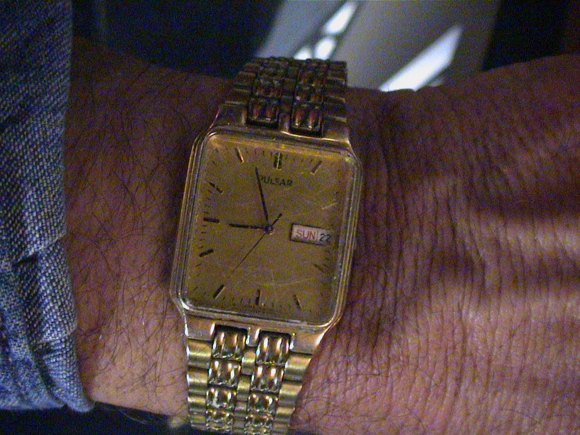 This golden wrist watch points at three minutes to nine.