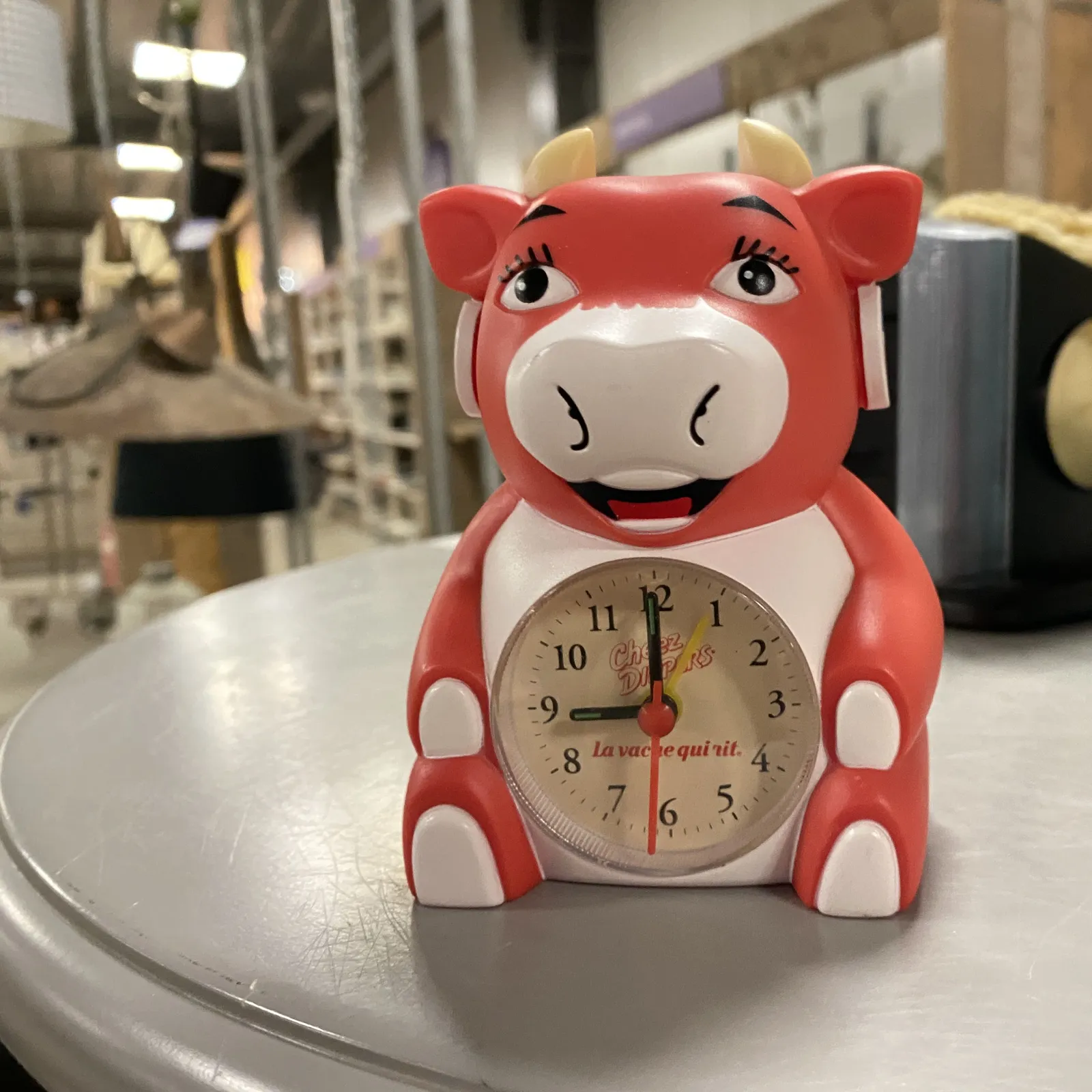 A clock in the shape of a bright red smiling cow, it also says La Vache Qui Rit on the clock’s face, just to be sure. The clock points at 1 minute to 9.