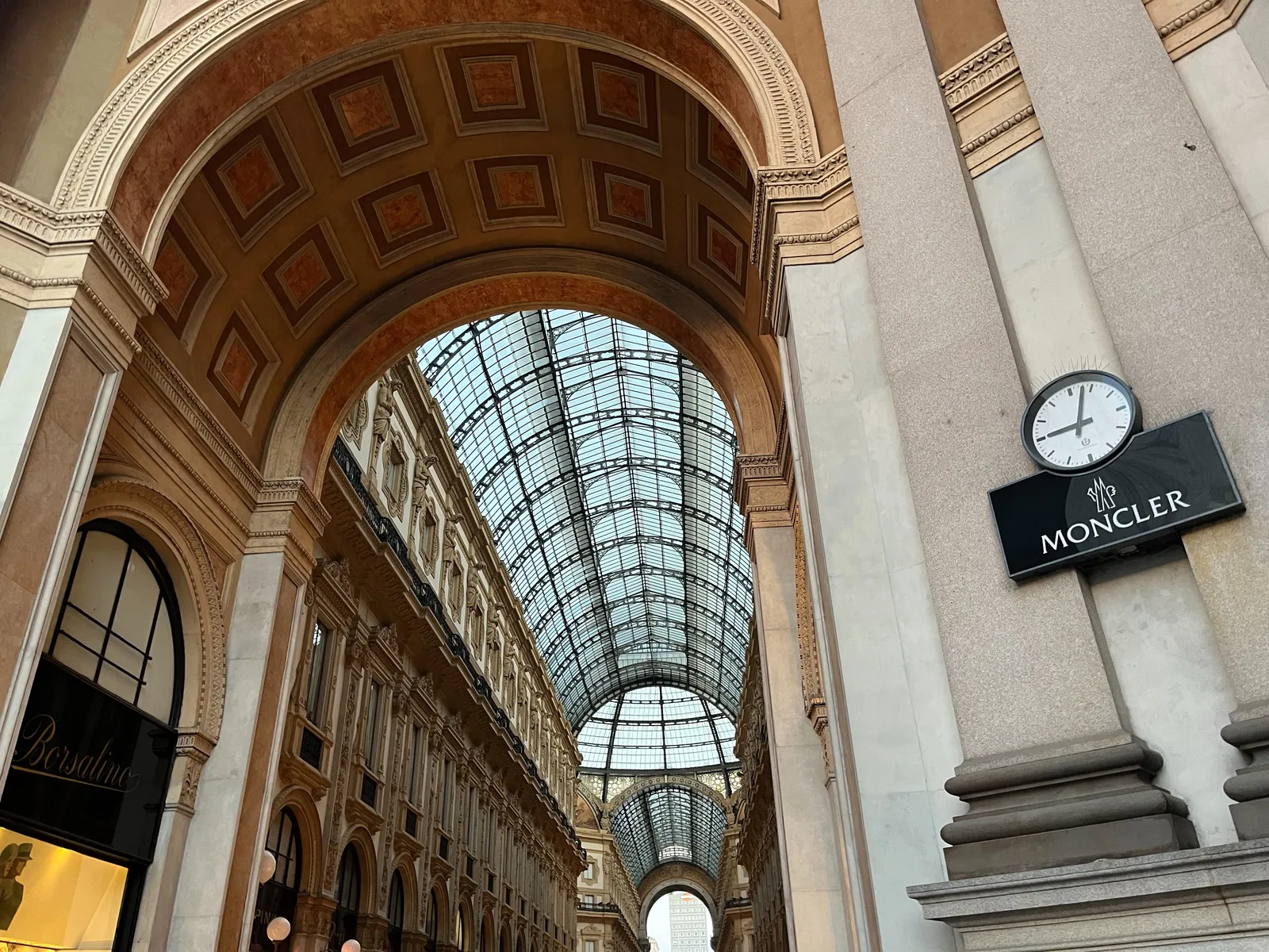 A very posh shopping street with a clock. The clock points at 3 minutes past 9.
