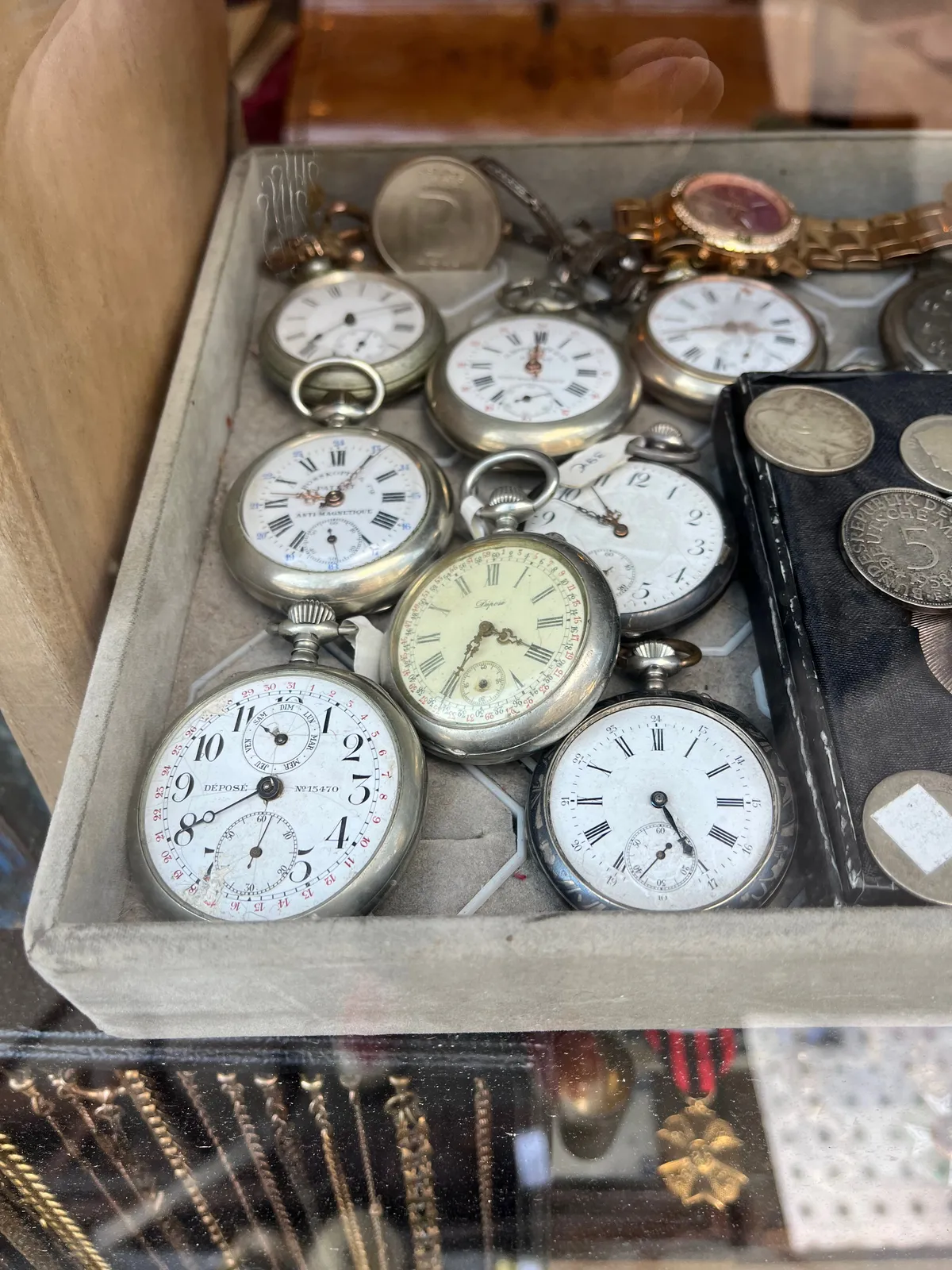 A box filled with old pocket watches. One if them points at 5 past 9.