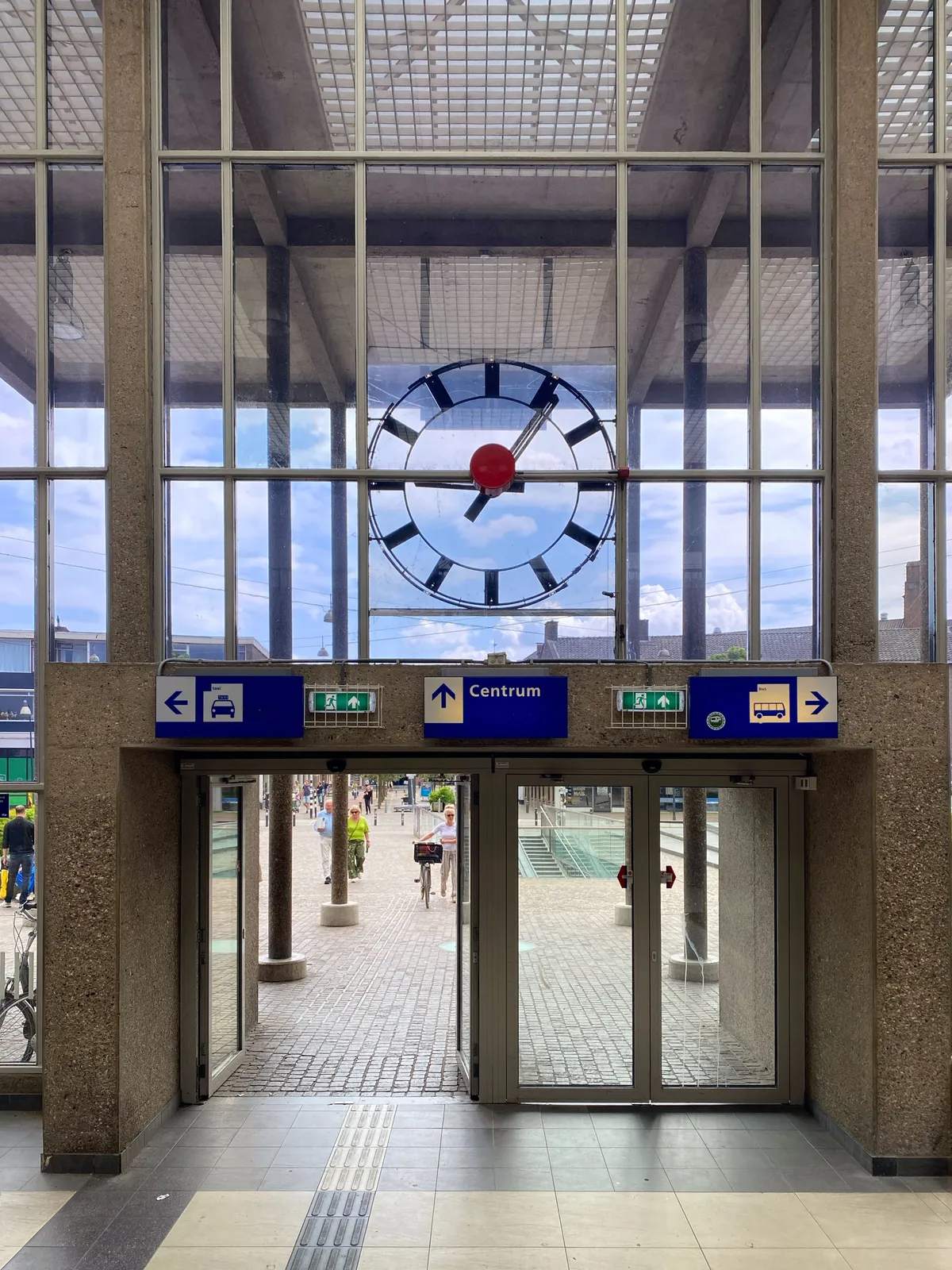 Peeking through a glass facade from the inside, to a clock that’s attached to the outside. It points at 6 minutes past 9 from this side of the building. From the outside it must show a completely different timestamp.