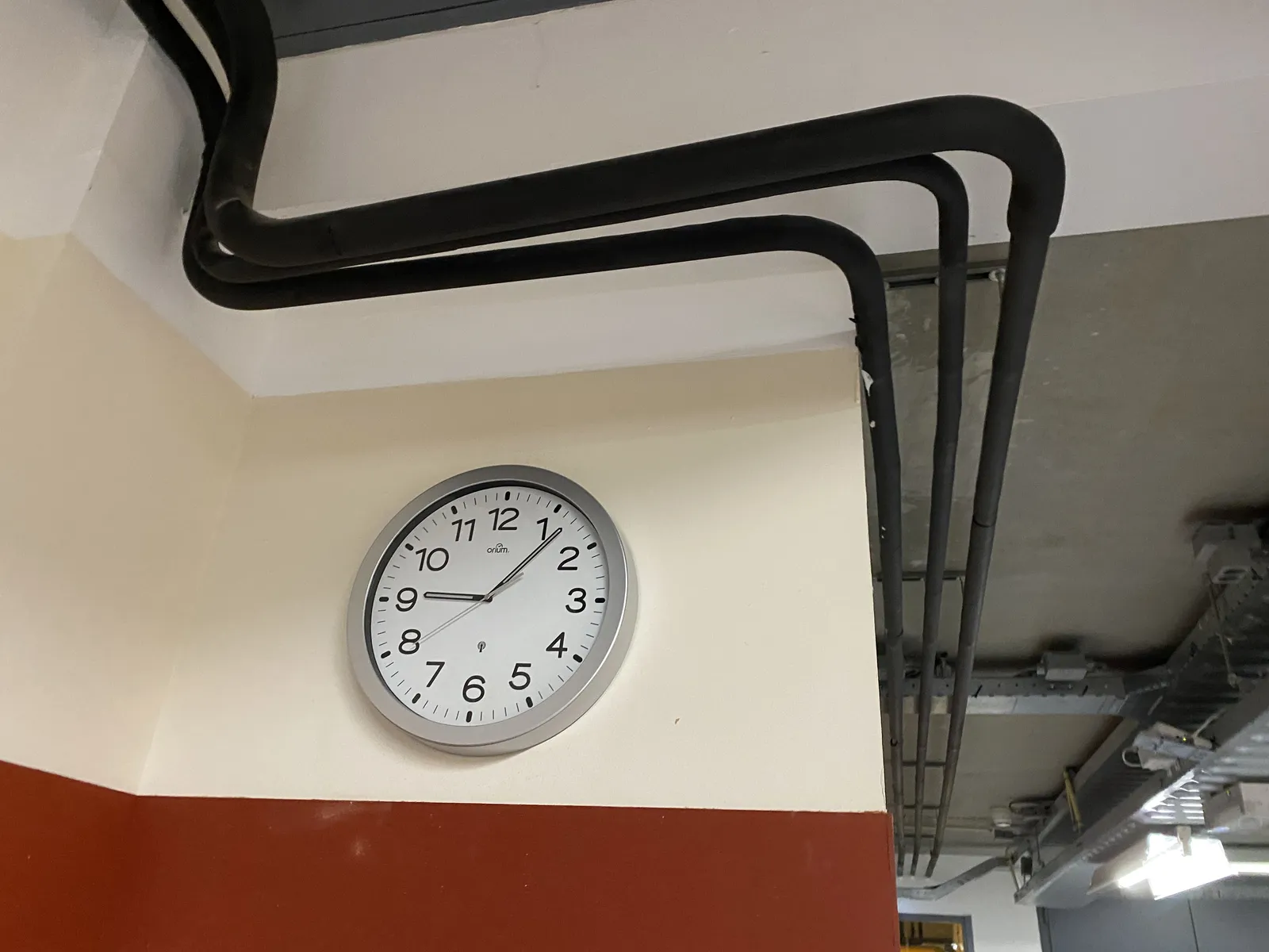 A clock in a part of a building where decoration is not of the highest priority. It points at 6 minutes past 9.