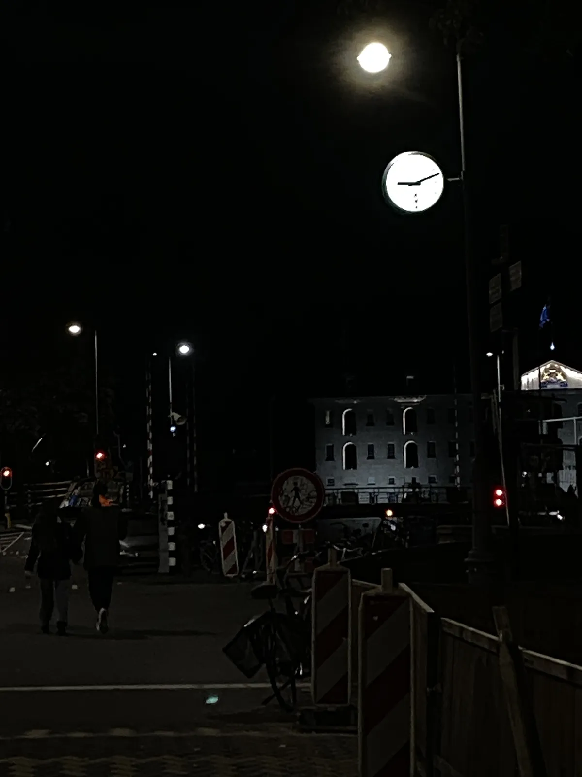 A slightly overexposed clock in dark Amsterdam. It points at 12 minutes past 9.
