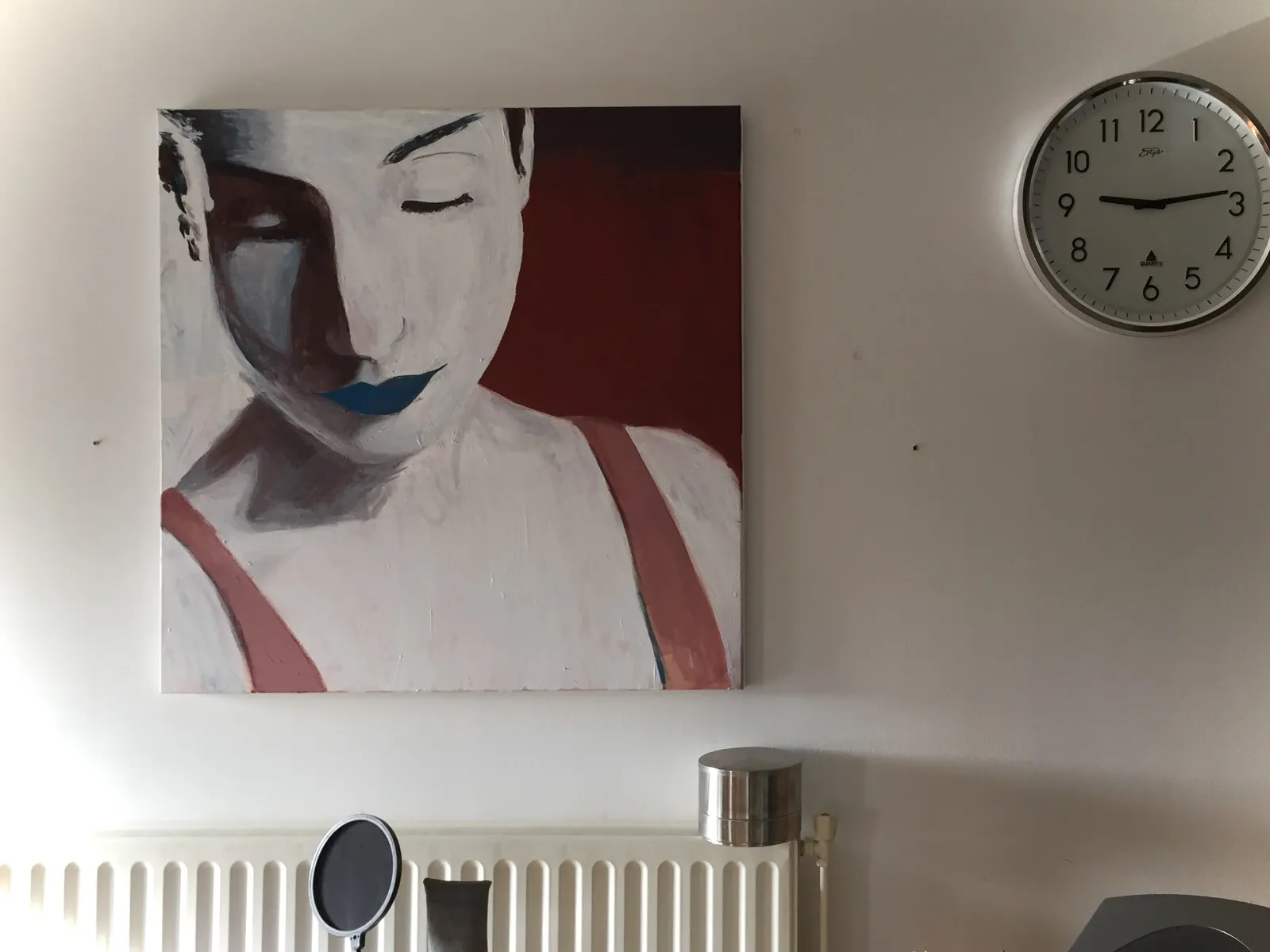 Next to this painting of a person there’s a clock. It points at 13 past nine.