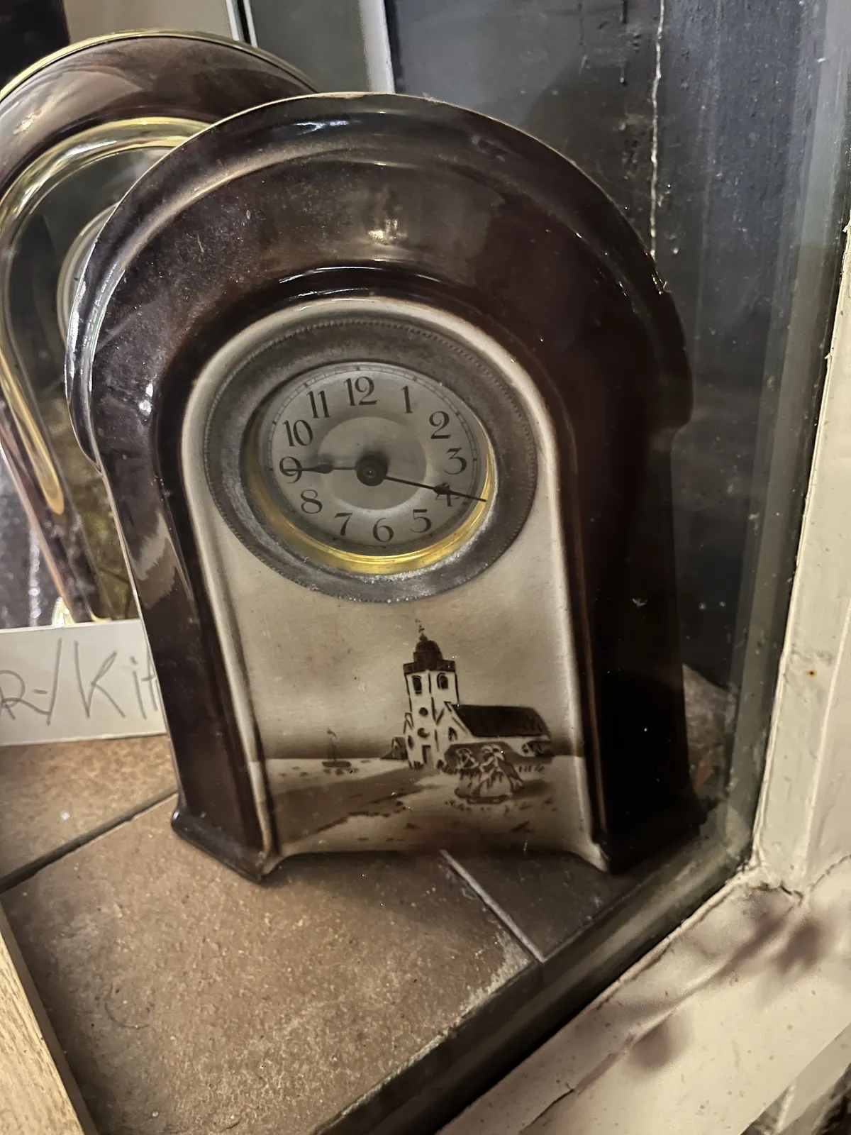 A small table clock with a church printed on it. The clock points at 19 minutes past nine.