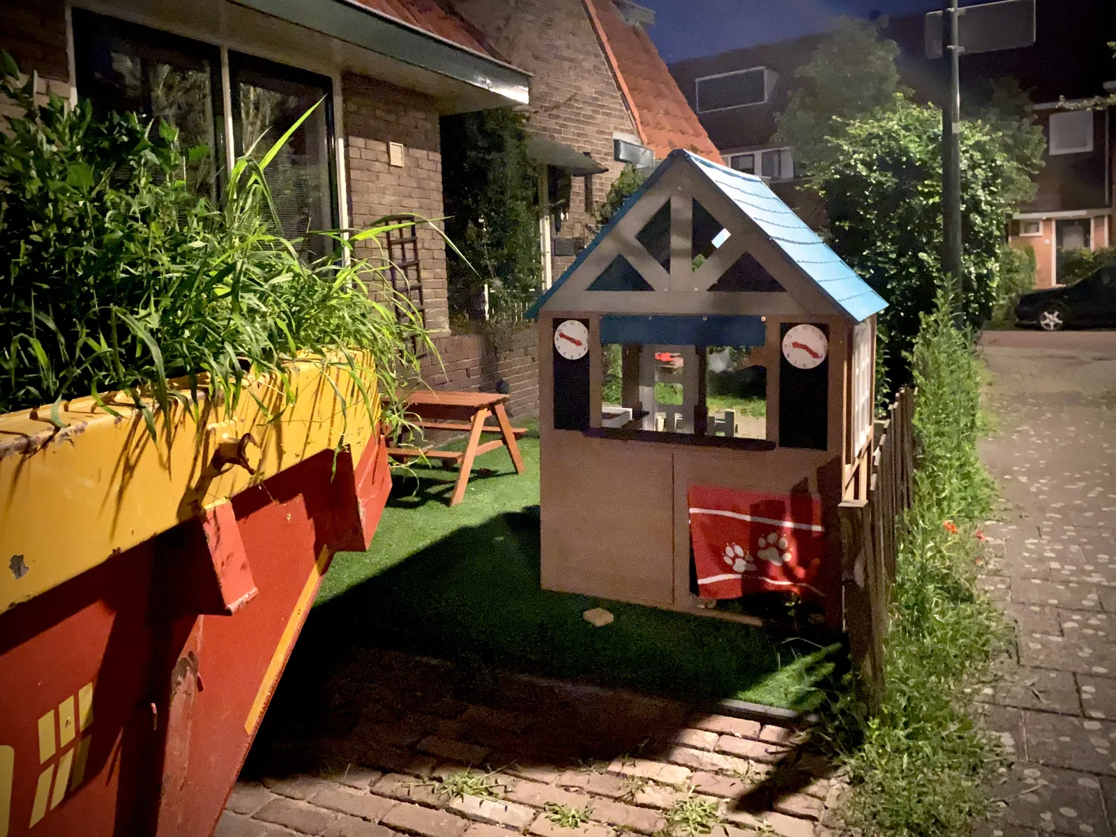 A children’s play house in a garden. There are two clocks on this house. One of them points at 12 minutes to 4, and the other one at 21 minutes past 9.