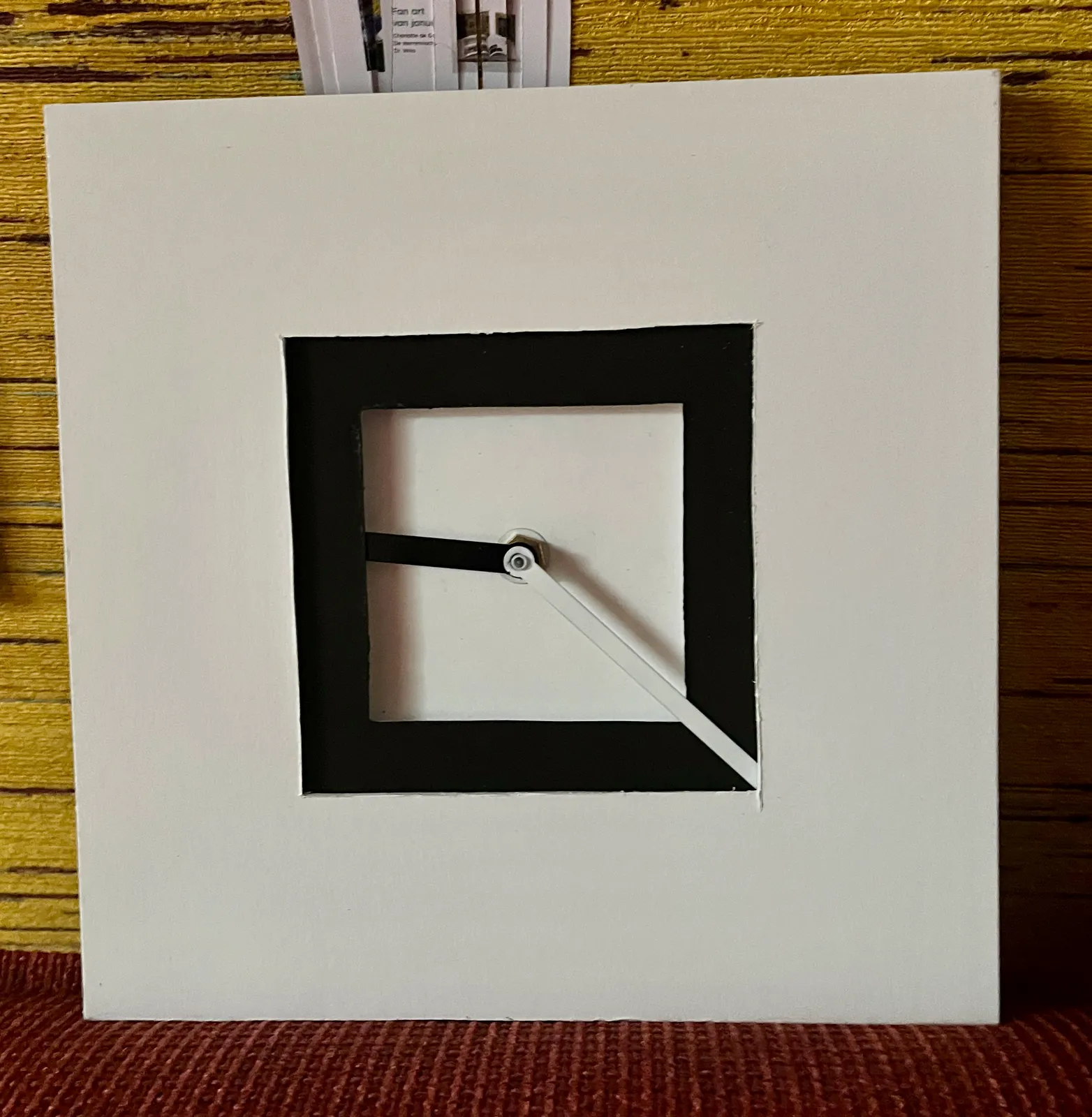 A minimalist, arty, geometric clock points at approximately 22 minutes past nine. Its proportions are such that at this exact time the minute hand is exactly twice as long as the hour hand.