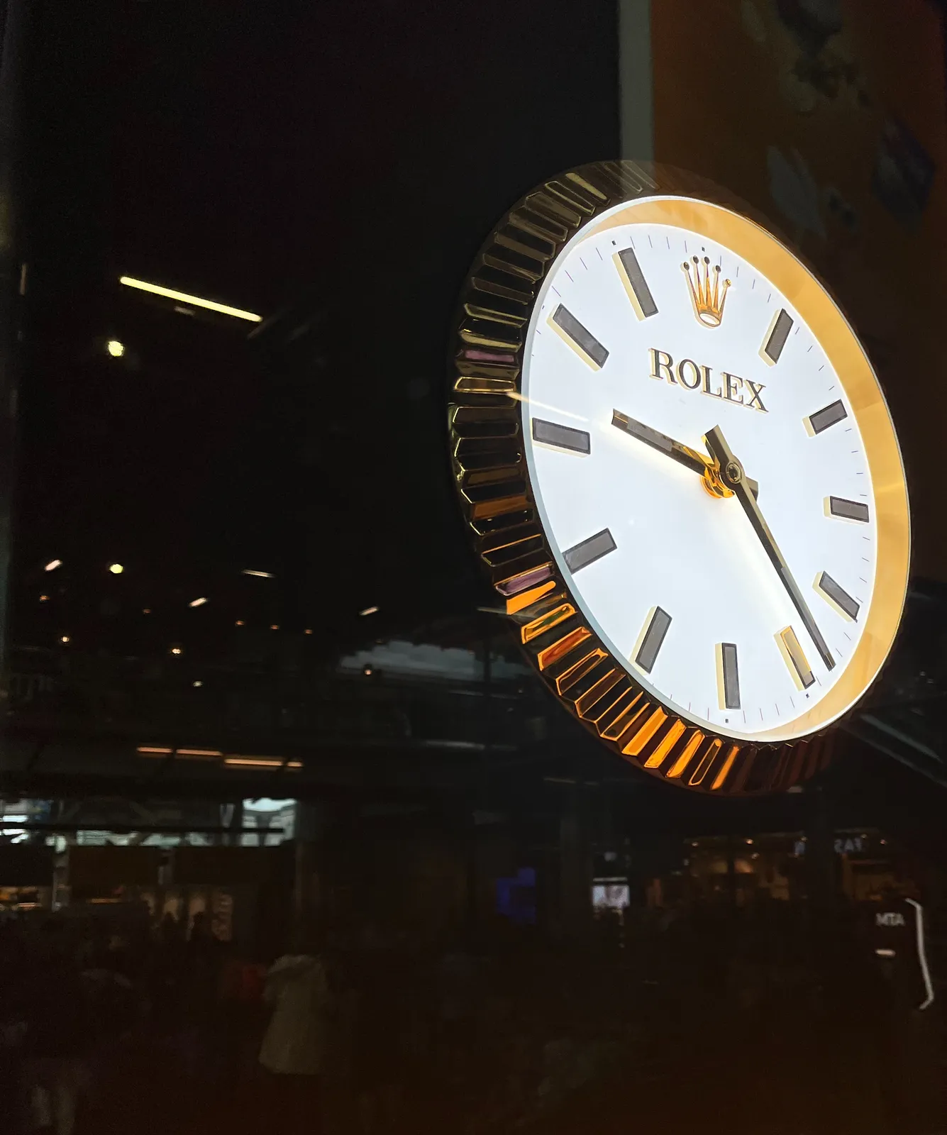 A huge shiny clock that points at 23 past 9.