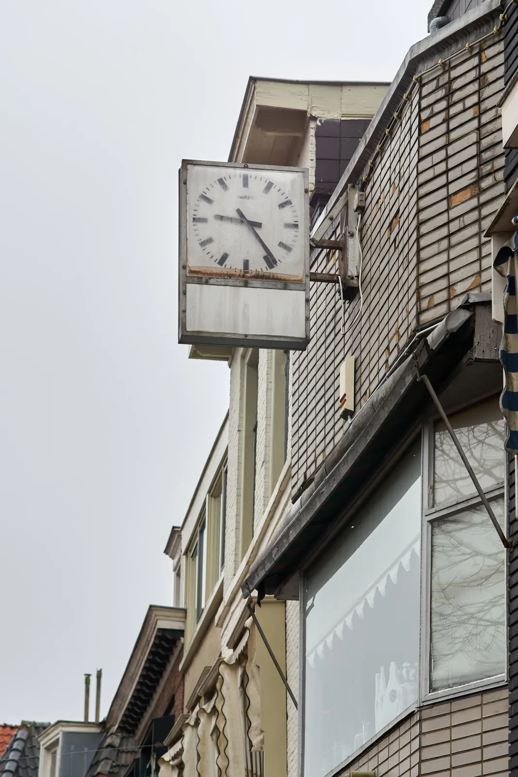 A clock attached to a building points at 24 past nine.