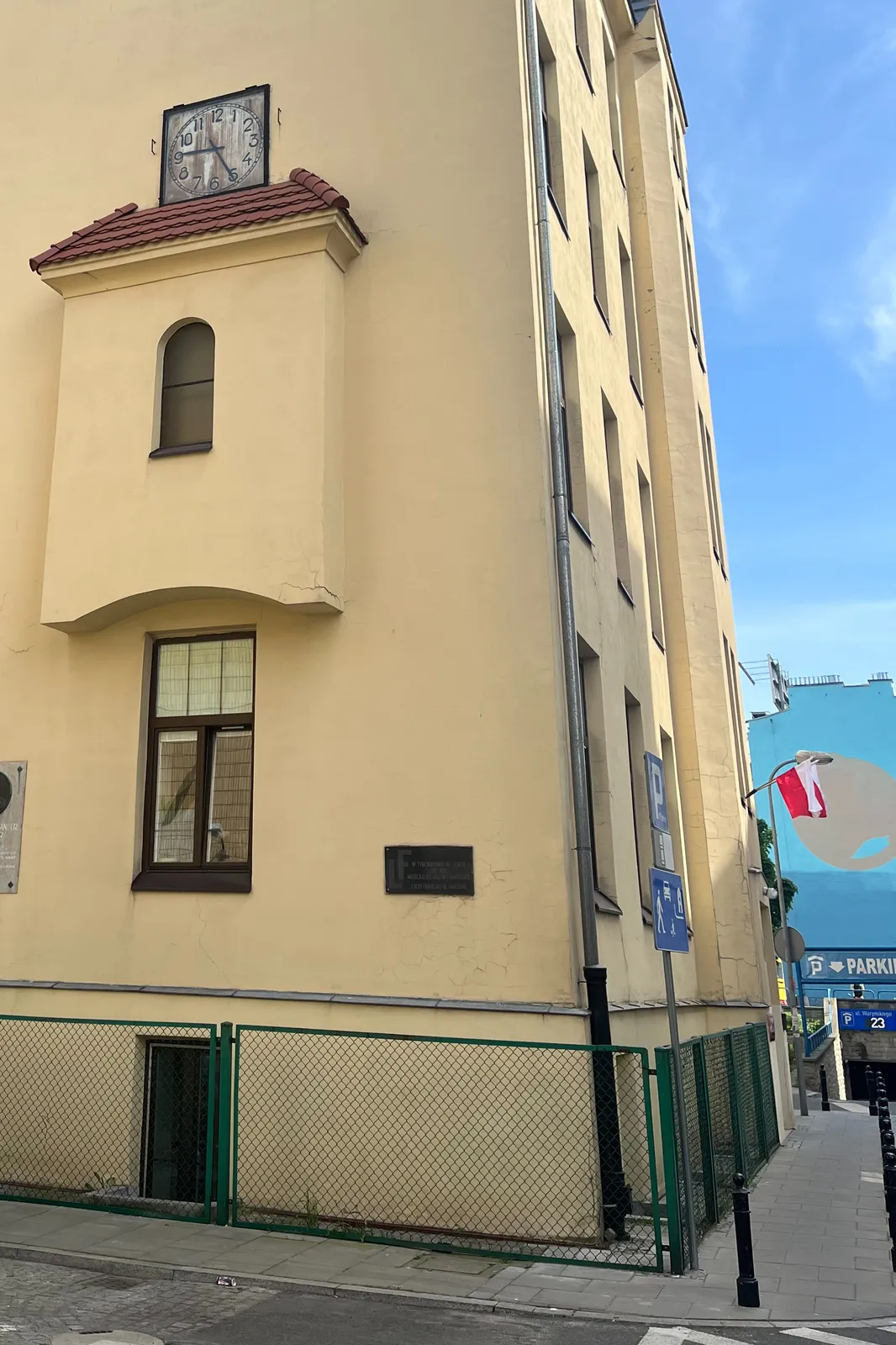 A clock on a yellow building. It points at 25 minutes past 9.