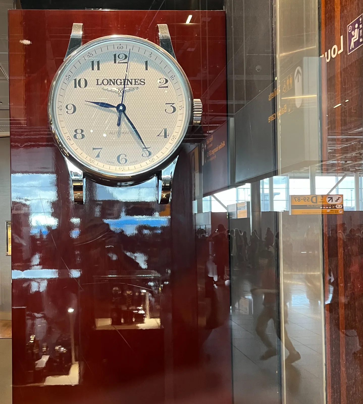 In the reflection of this window you can see that this picture is taken on an airport. Some people running, other idling. Behind the window there’s a clock which points at 25 past nine.